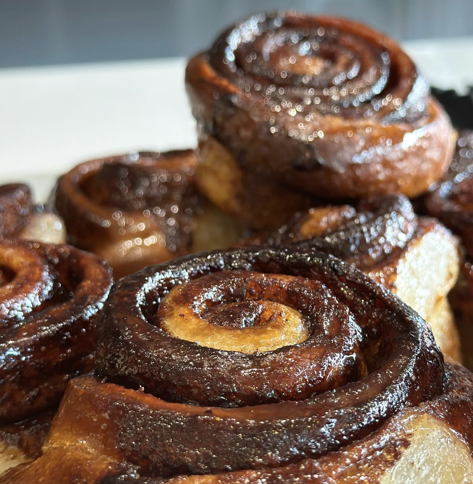Close-up of glazed cinnamon rolls with a shiny caramelized exterior and swirled inside.