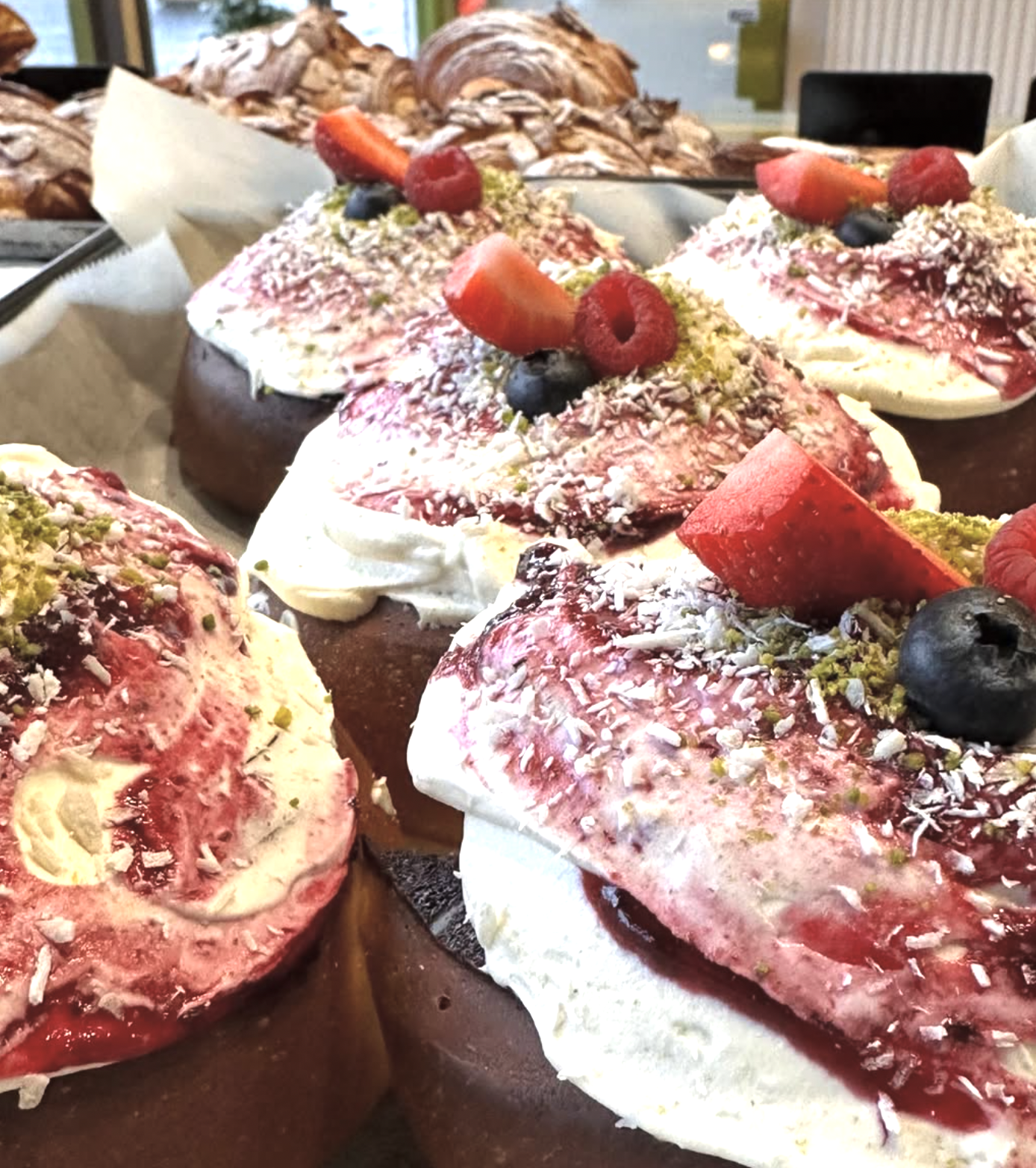 Dessert topped with fresh strawberries, blueberries, raspberries, shredded coconut, and chopped pistachios.