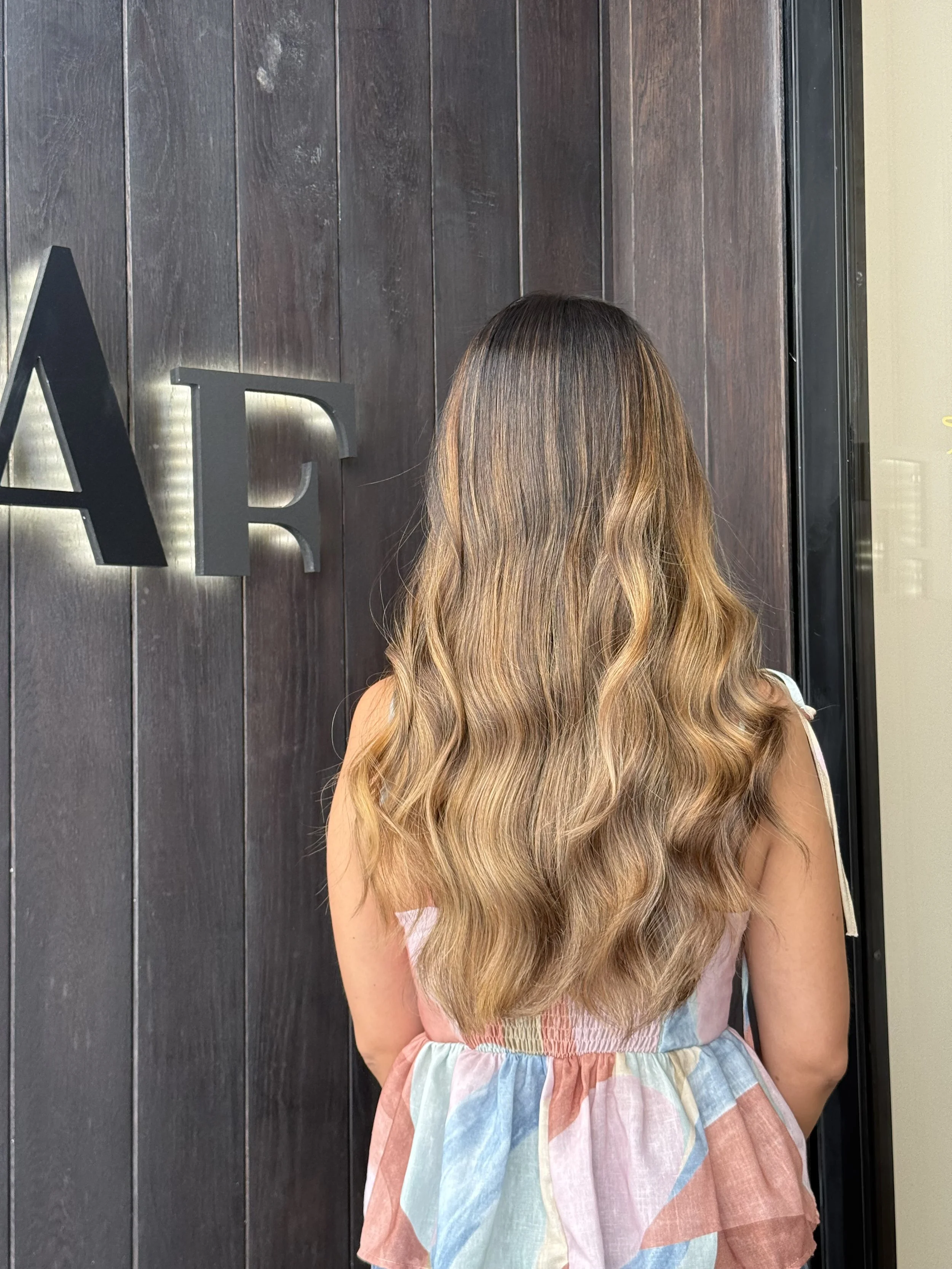 Balayage oscuro a rubio con transición suave y ondas naturales, técnica de color avanzada en AF Boutique Barcelona.