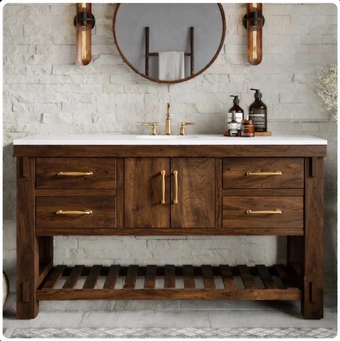 A rustic bathroom vanity with a white countertop, gold fixtures, and dark wooden cabinets, with a round mirror and wall-mounted light fixtures above.