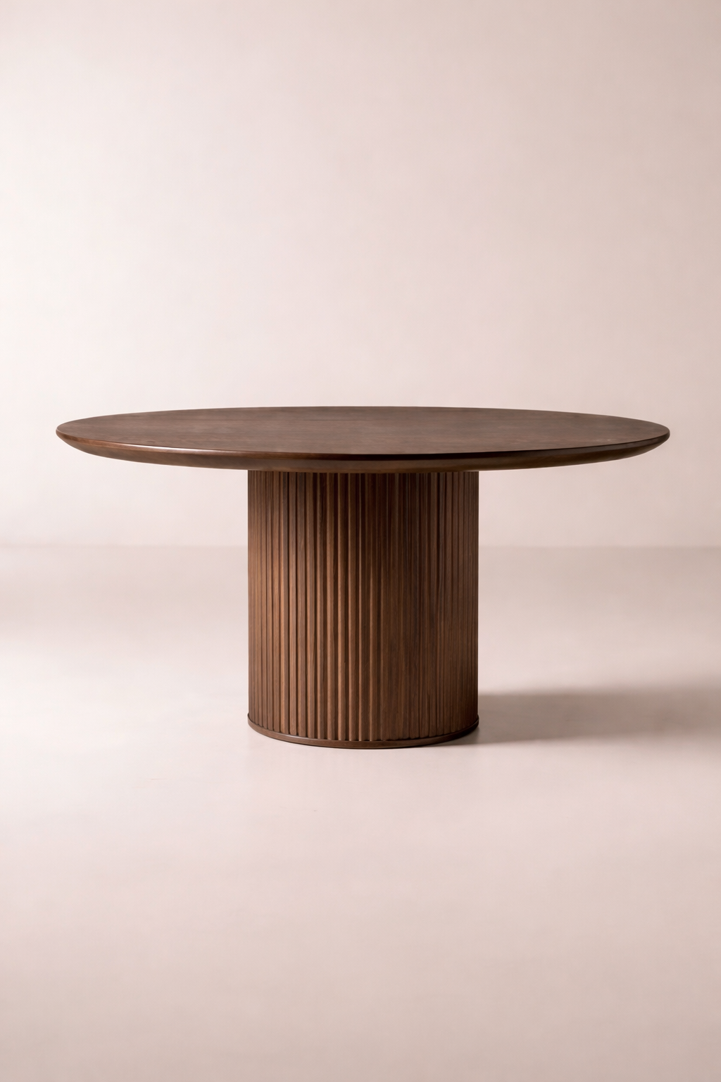 A round wooden table with a cylindrical base featuring vertical slats, set against a plain light background.