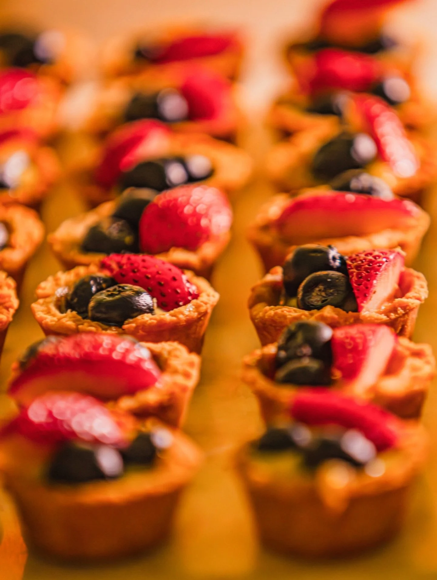 Mini fruit tarts topped with strawberries, blueberries, and raspberries.