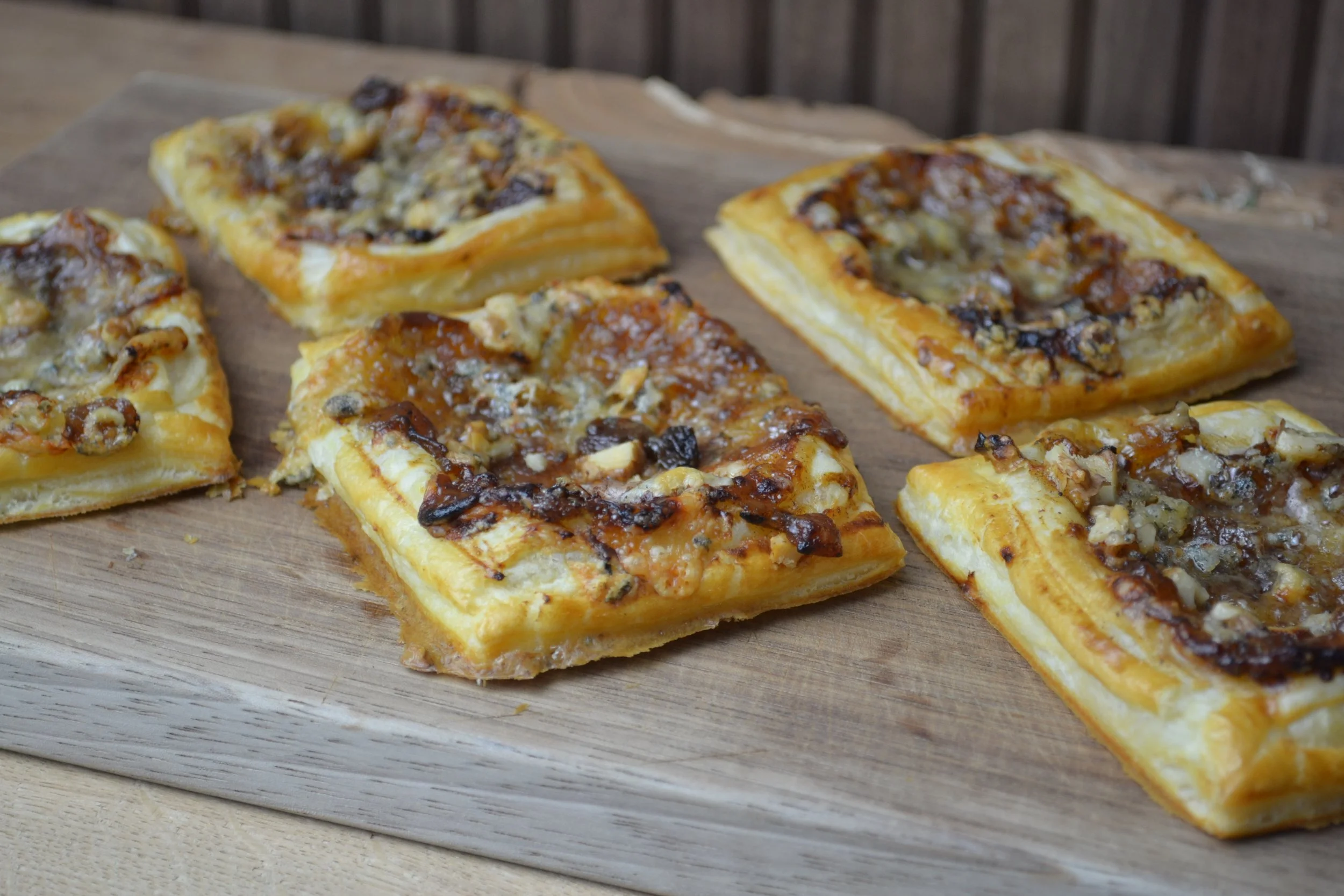 Sliced Spanakopita on wooden board with flaky golden pastry crust and spinach filling