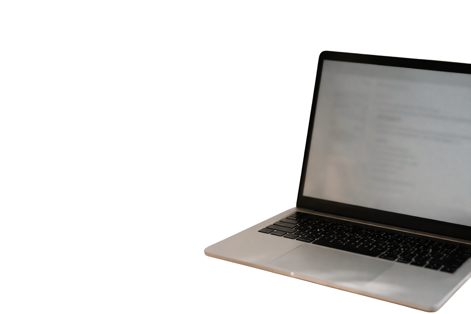 A silver laptop with a black keyboard and a blurred screen positioned against a black background.