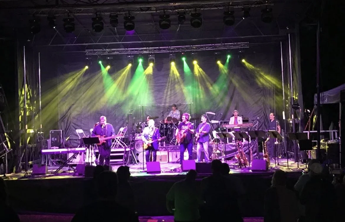 Band performing live on stage with colorful stage lights and audience watching.