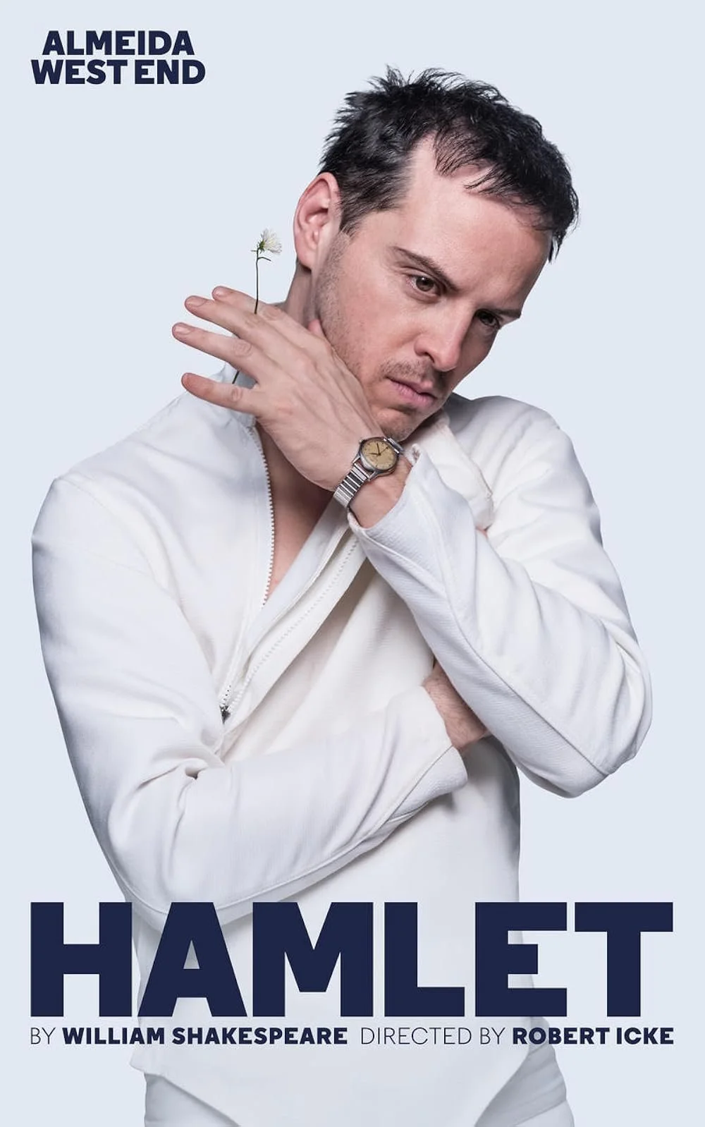 Promotional poster for the play Hamlet with a man in a white jacket looking down thoughtfully, holding his shoulder with a small flower behind his shoulder, against a light background. The text includes 'Almeida West End,' 'Hamlet,' 'by William Shake