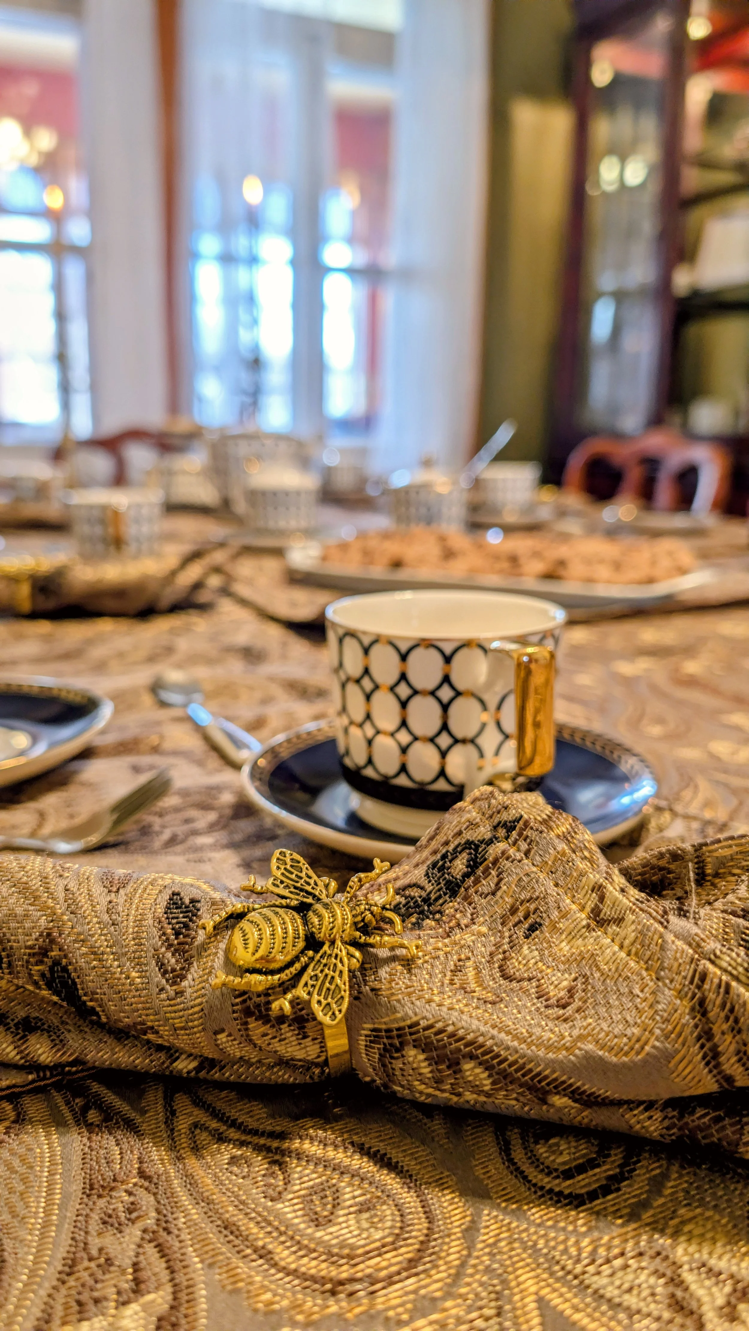 Vue rapprochée de la salle à dîner, dans laquelle les petits déjeuners sont servis. La vaisselle dorée avec un motif à la française et les serviettes en tissu donnent un air haut de gamme et chaleureux au repas pris en famille, en couple ou entre ami