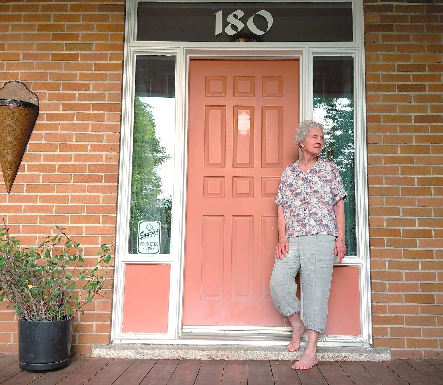 Voyageuse prenant la pose devant l'entrée principale de la Maison La Miellée, pendant une belle journée d'été