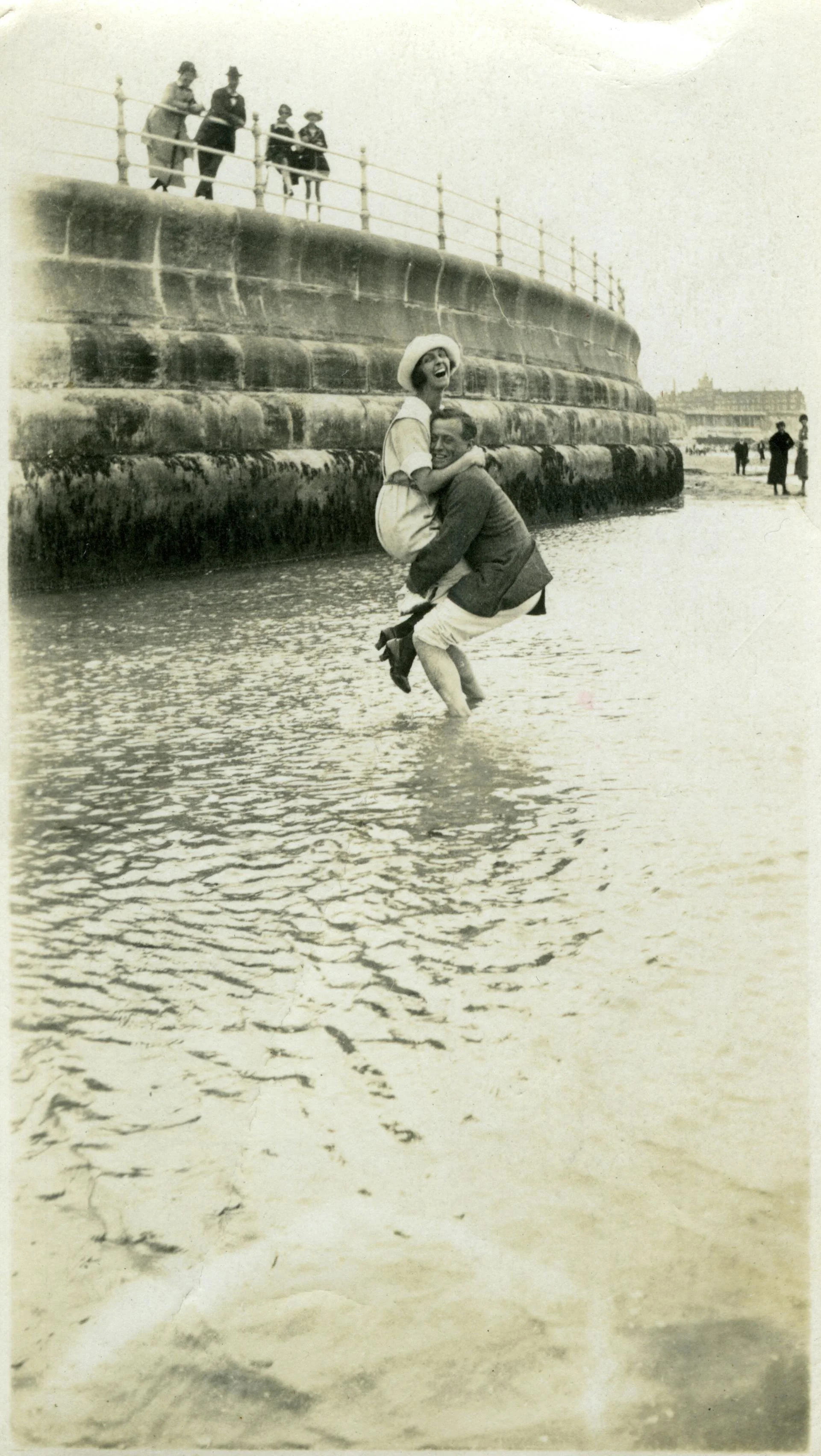 Vintage photo of a couple embrace playfully, standing in water.