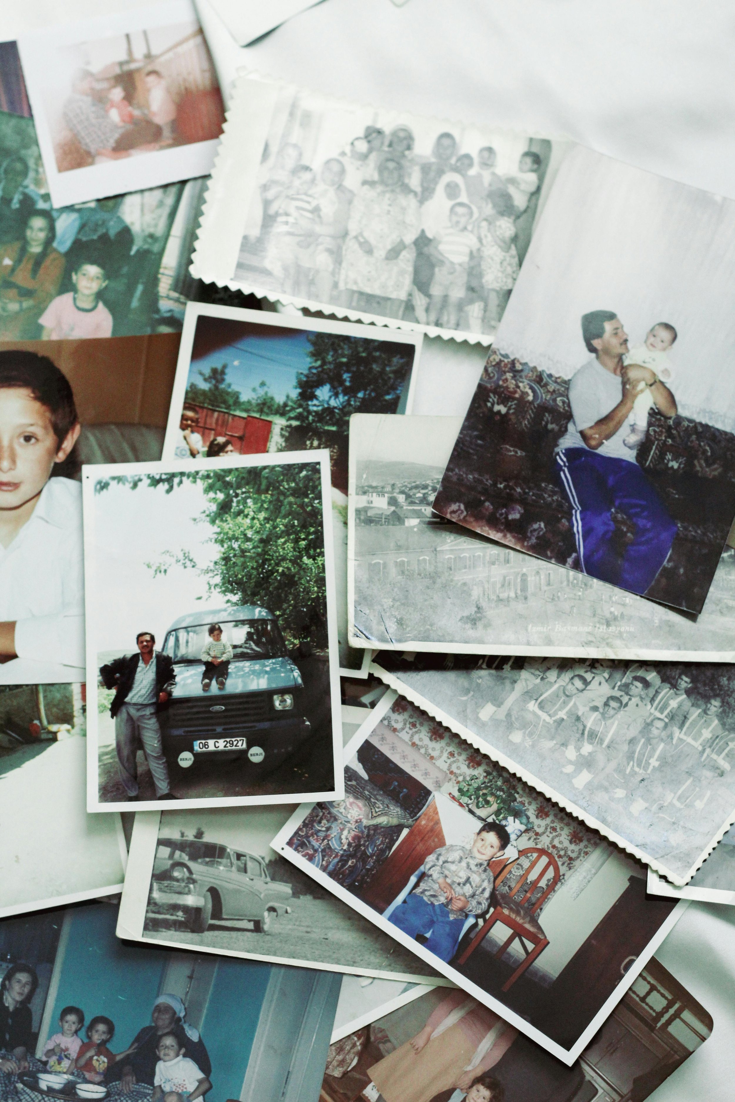 A collection of old family photographs spread out on a surface, including portraits, outdoor and indoor shots, and images of children and adults from different times.