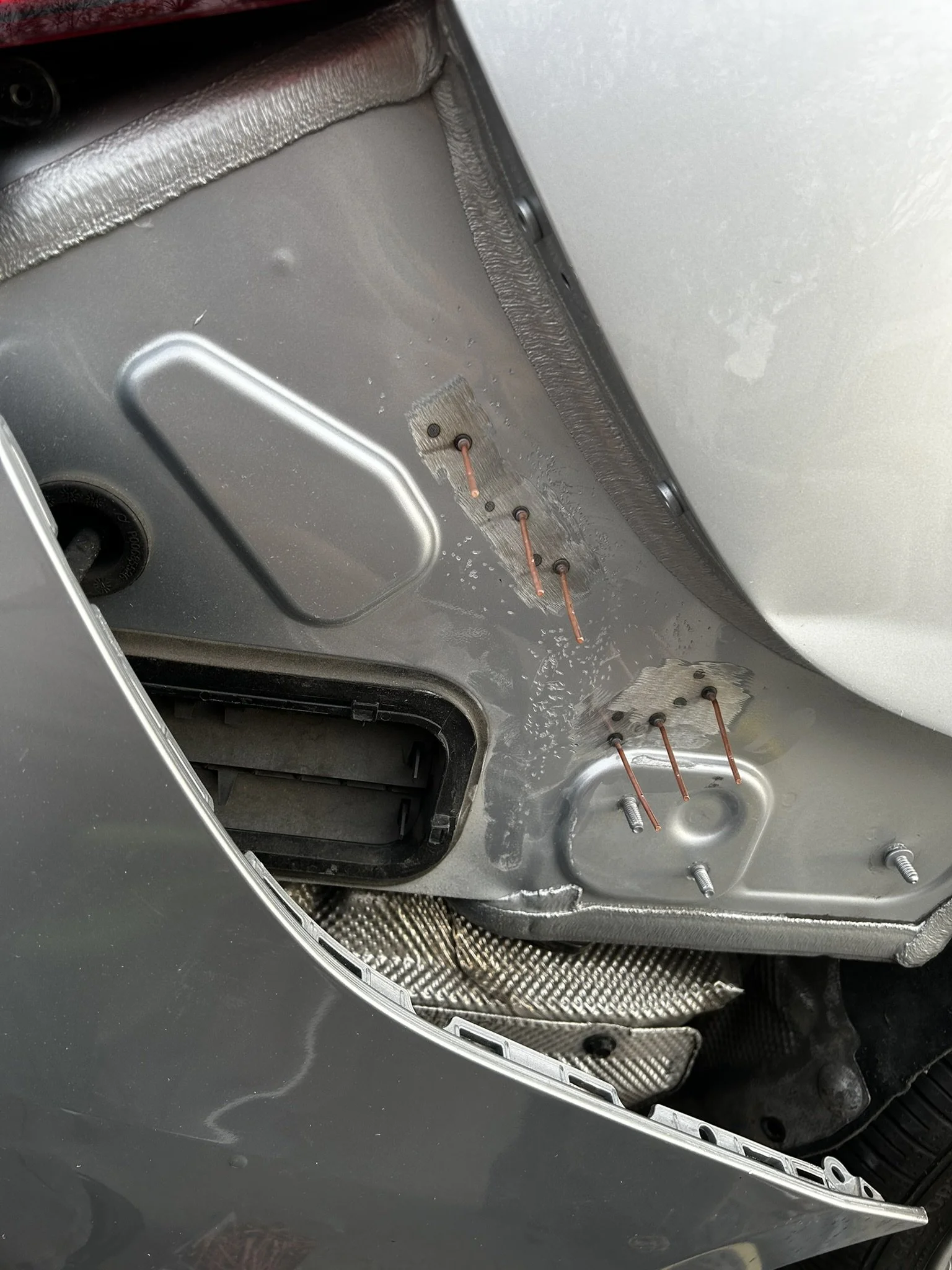 Close-up view of a car's interior with the door panel removed, exposing the metal frame, electrical connections with copper wires, and some insulation material.