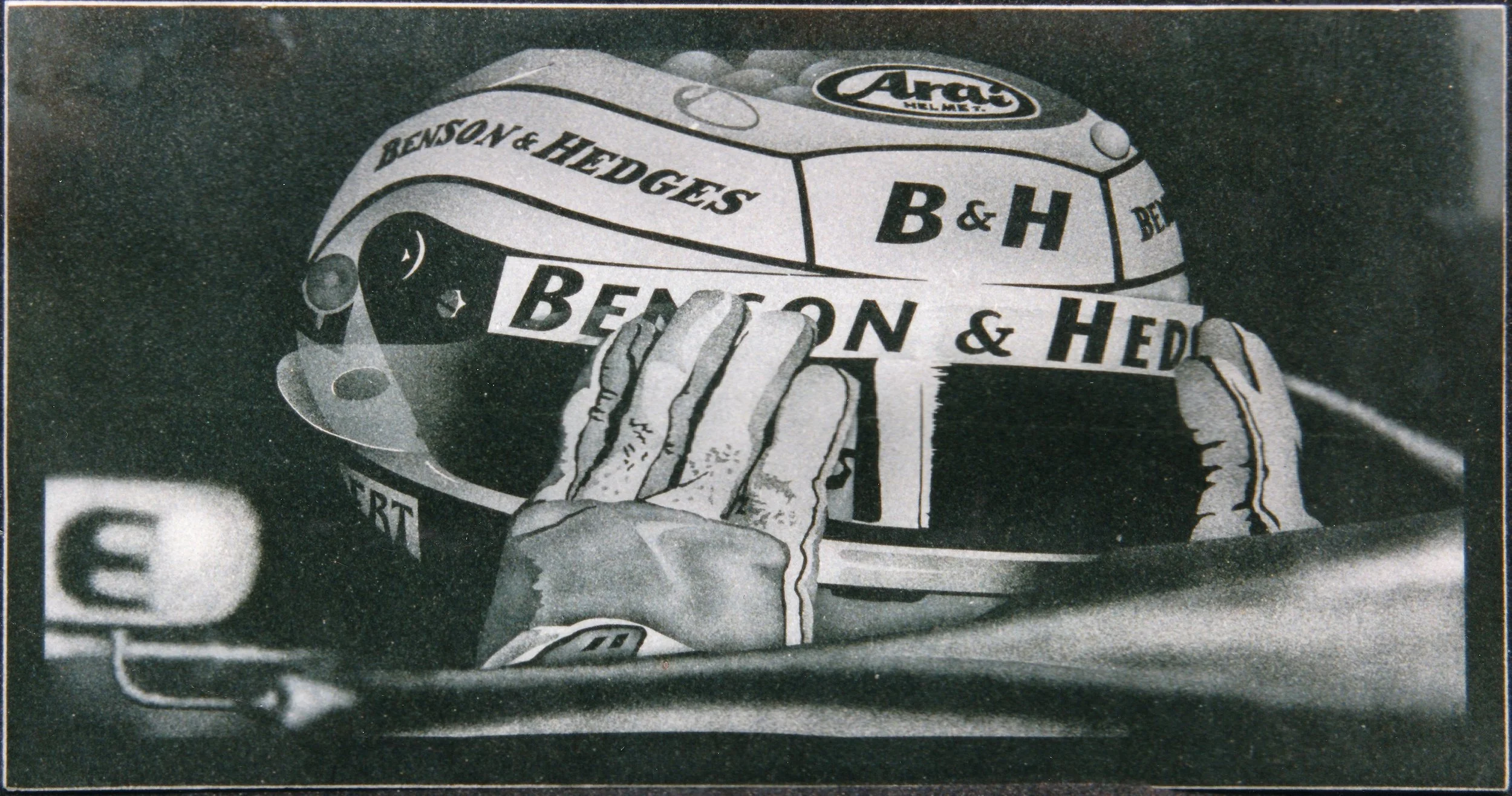 Etched artwork, on polished black granite, of a racing F1 driver's helmet being held by gloved hands, displayed by the Jordan team at the Silverstone Grand Prix.