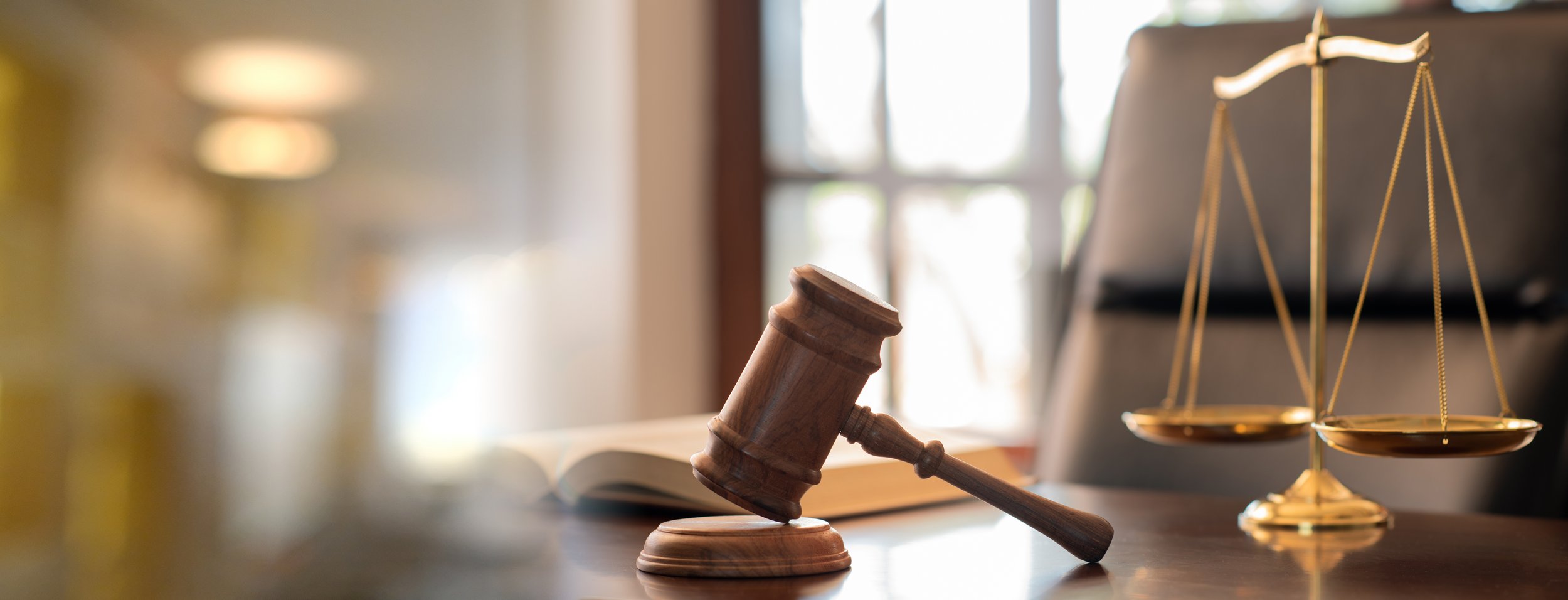 Judge's gavel, scales of justice, and law book representing notarized translation services.