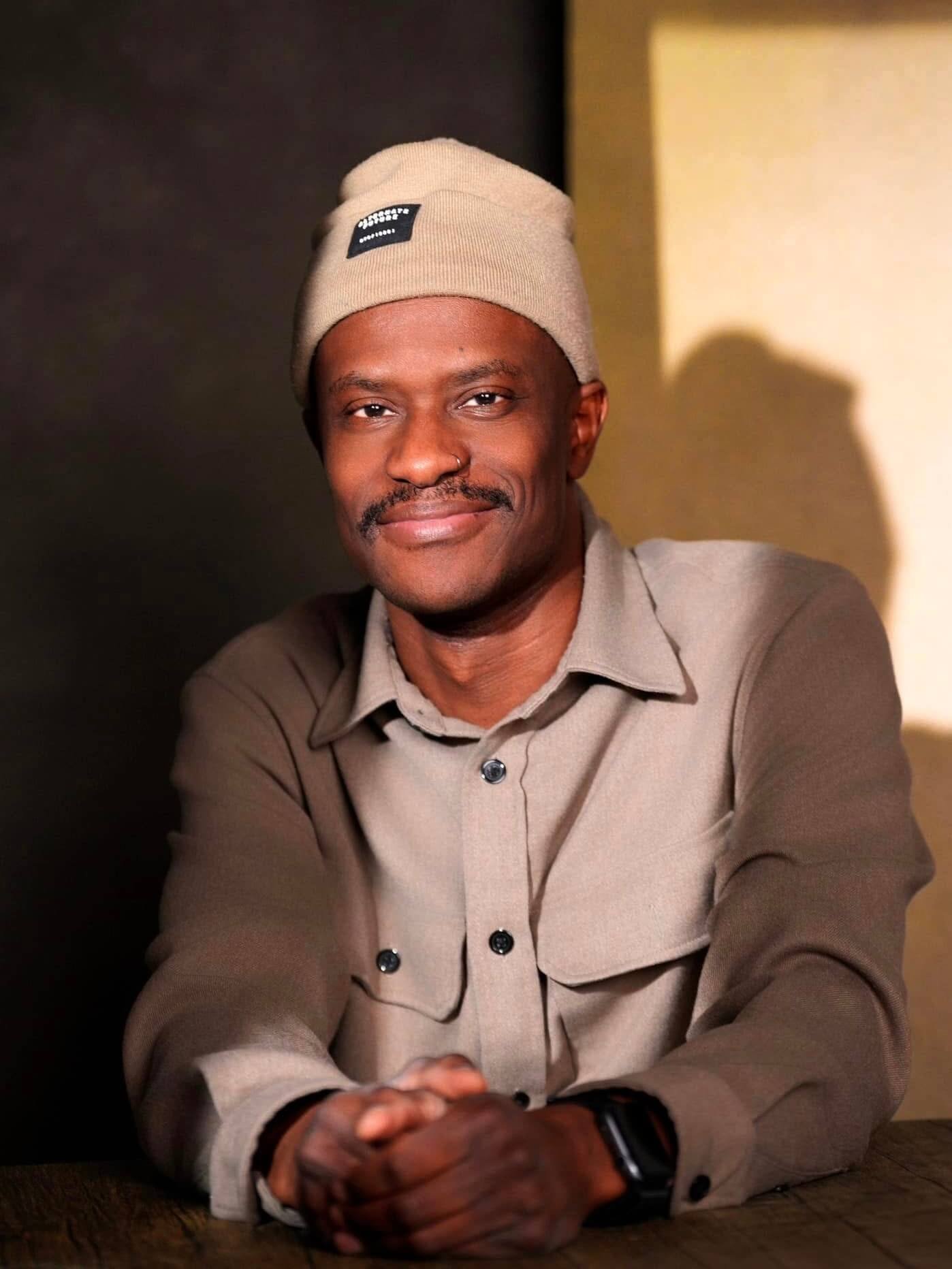 Professional headshot of a man in neutral tones with a dark background, relaxed corporate portrait.