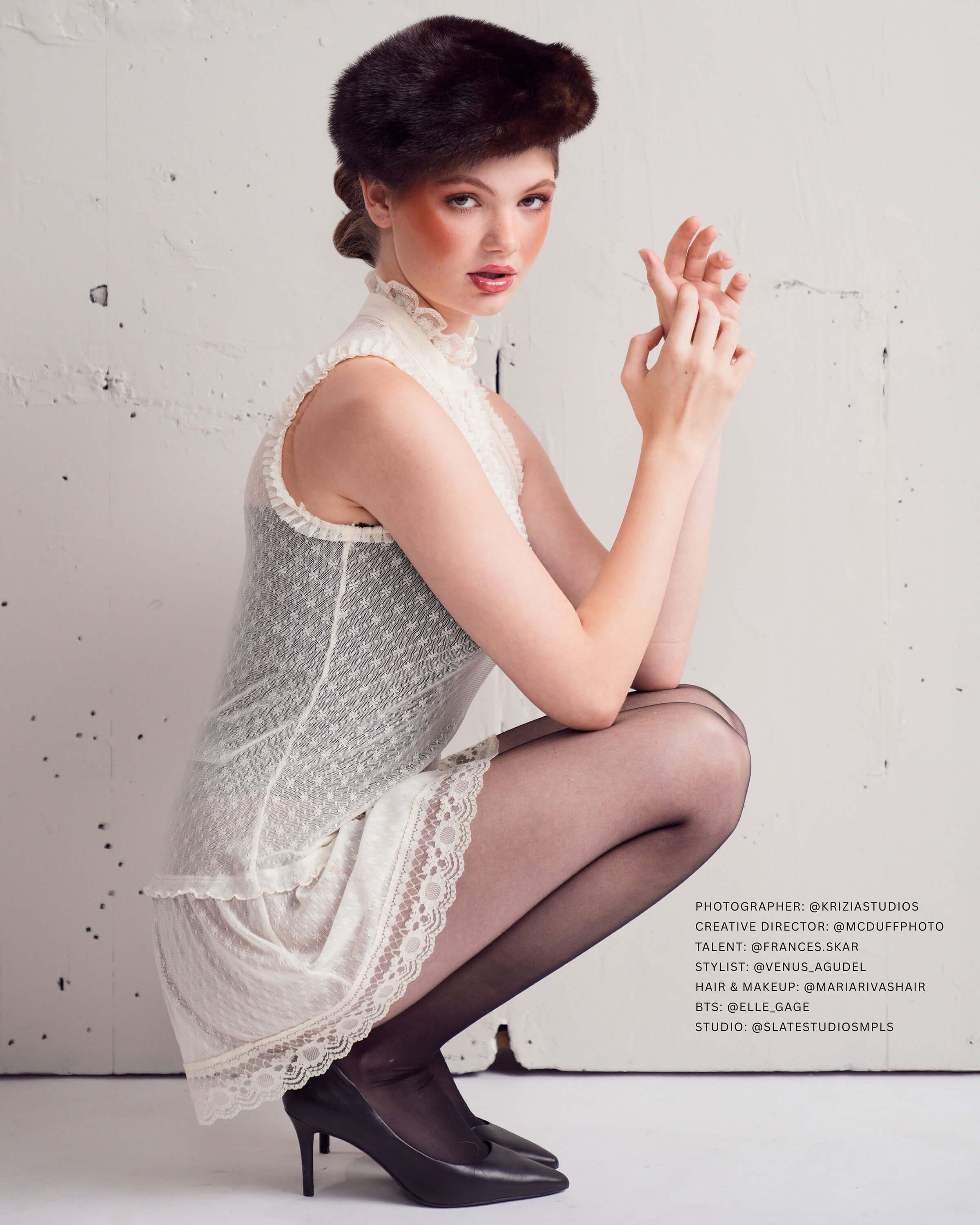 Studio fashion photograph of a model in a vintage lace dress and heels against a textured backdrop, created for an editorial and commercial fashion campaign
