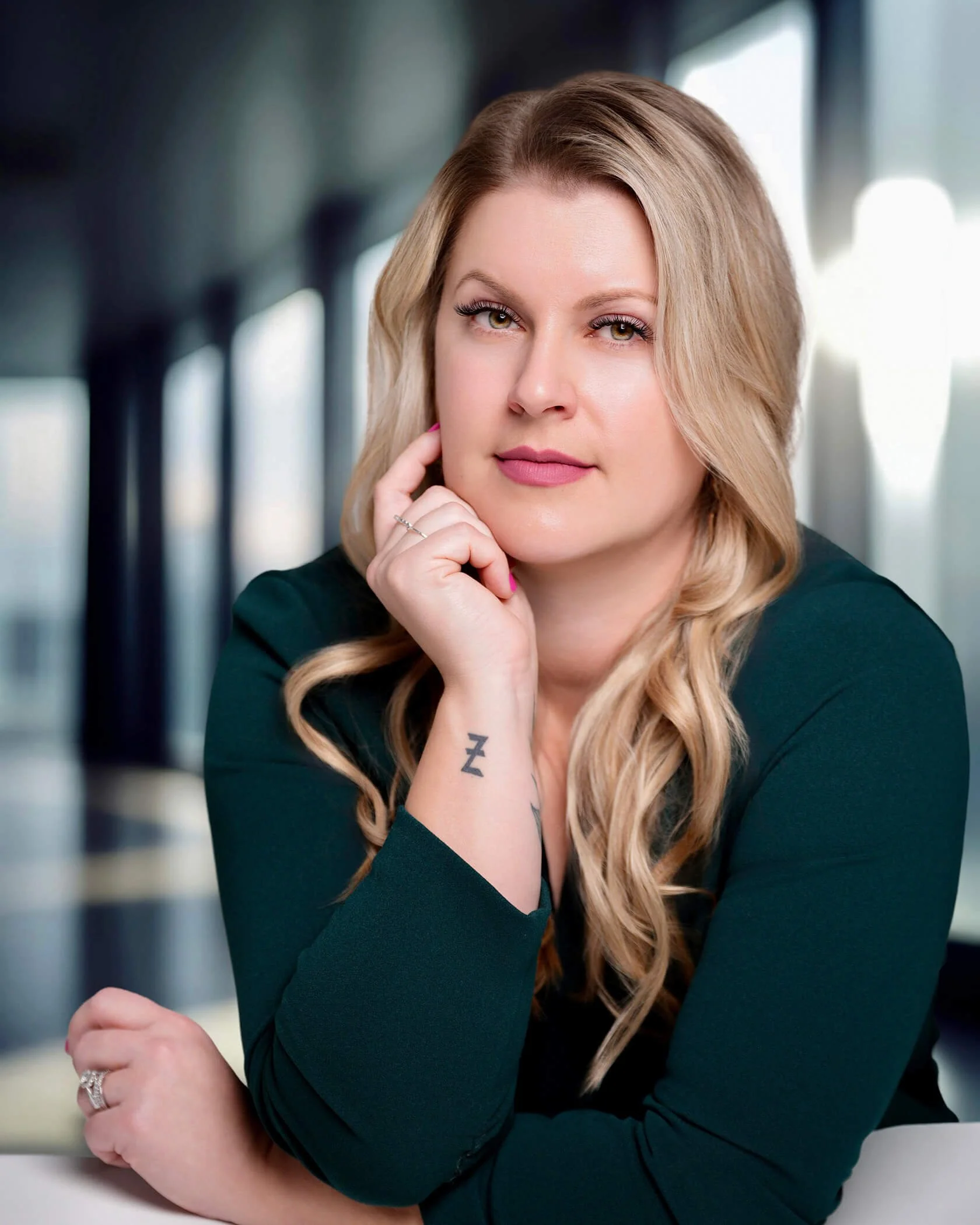 Professional headshot of a woman in a green top with soft indoor lighting and blurred background.