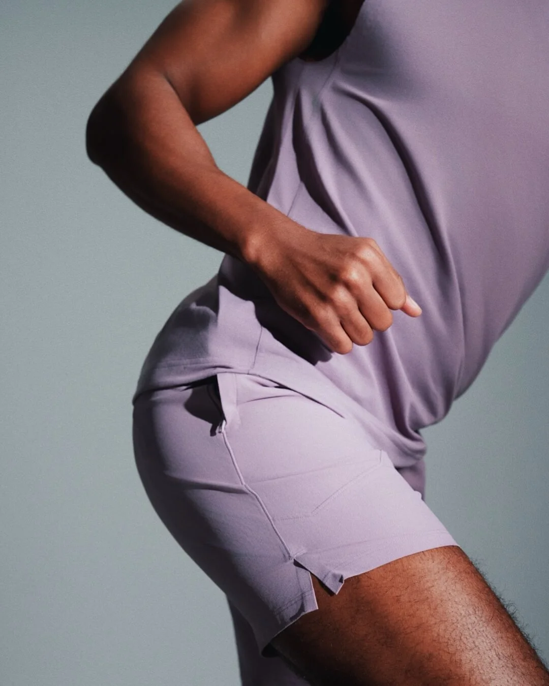 A person wearing a lavender athletic outfit, including a sleeveless shirt and shorts, against a neutral background.