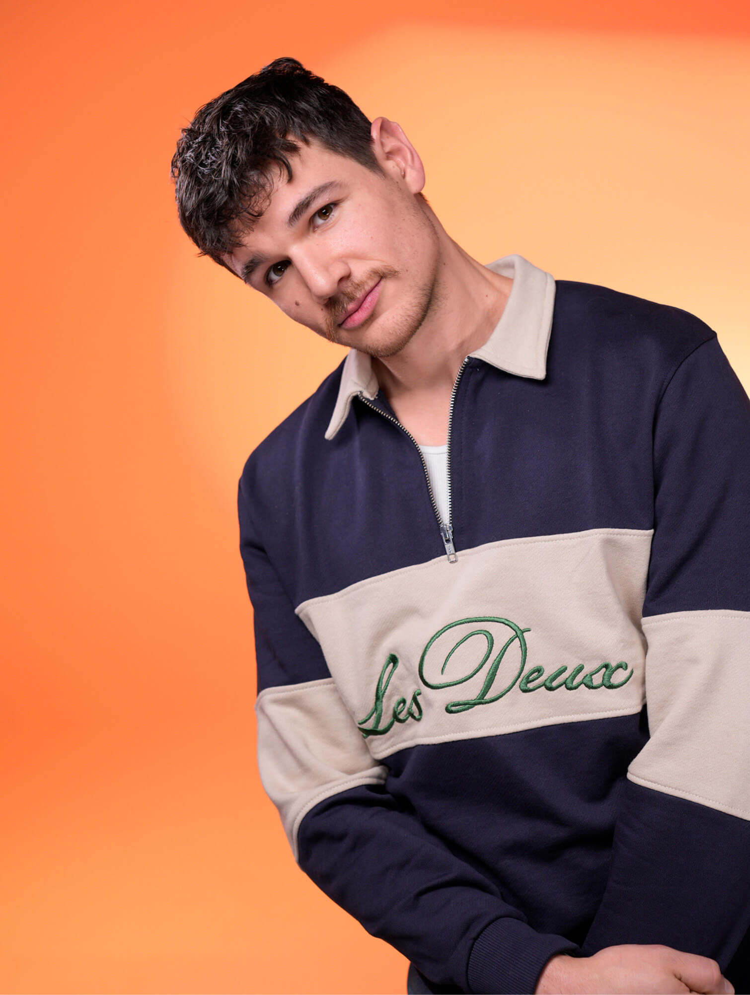 Modern corporate headshot of a young man against a peach gradient background, professional portrat