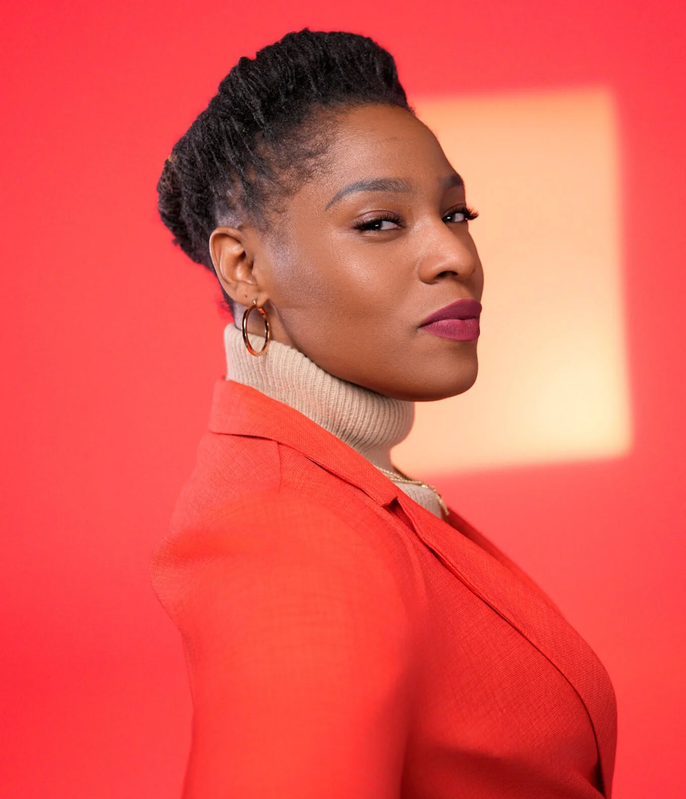 Profesisonal creative headshot of a woman in a red blazer against a bold red background, modern executive portrait in Minneapolis studio.