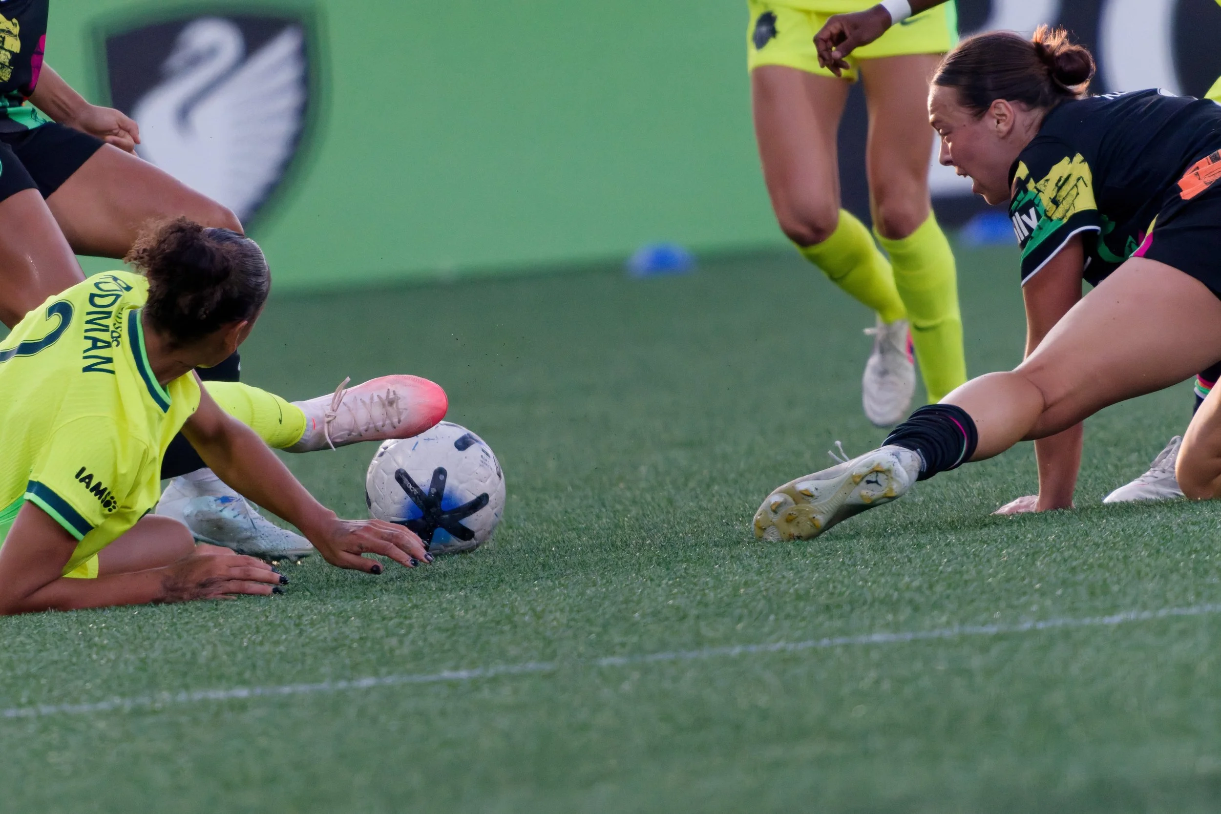 Women hockey players in black and yellow uniforms competing for the ball on the field.