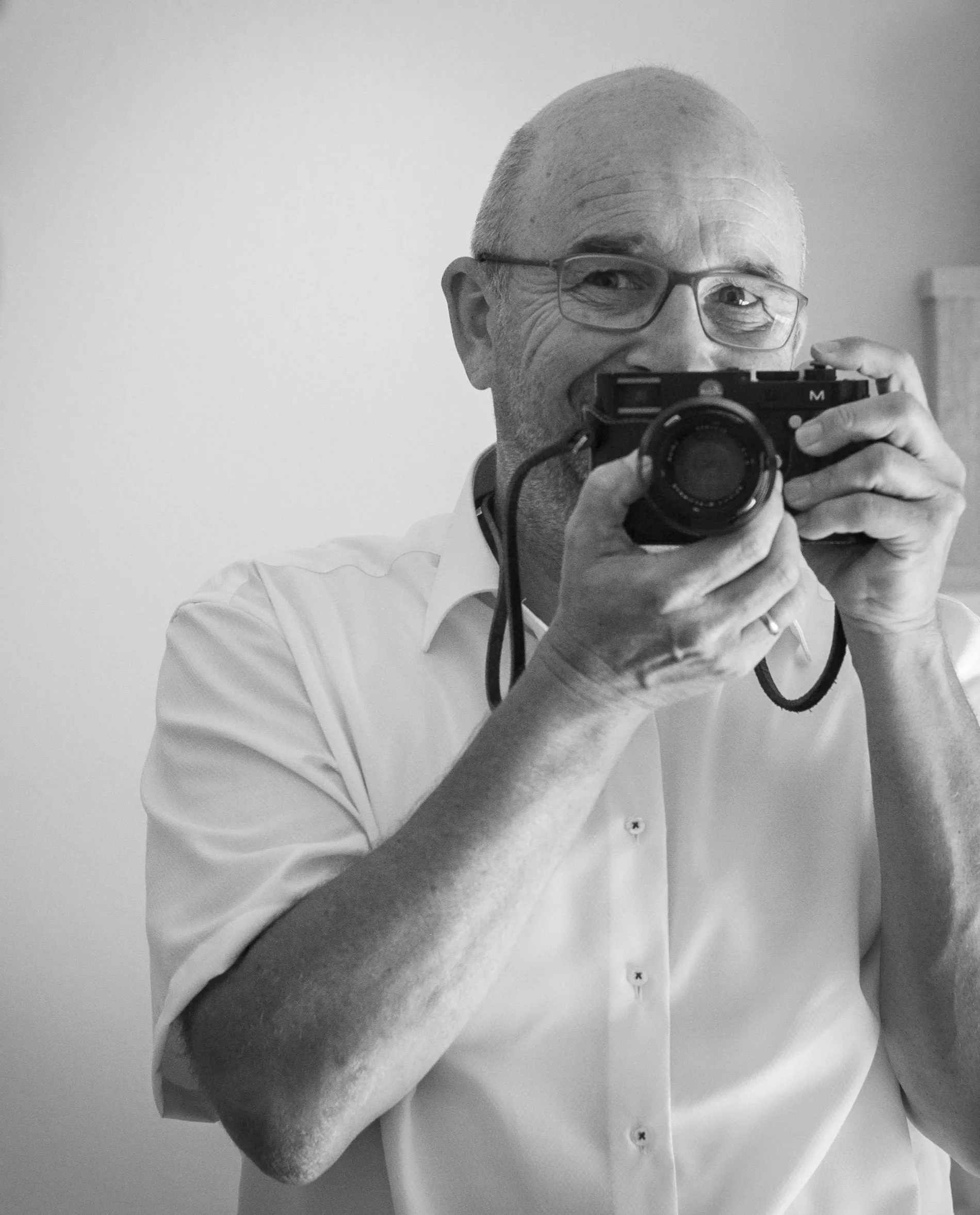 Peter Ritter fotografiert sich selbst vor einem Spiegel mit einer Kamera in schwarz-weiß