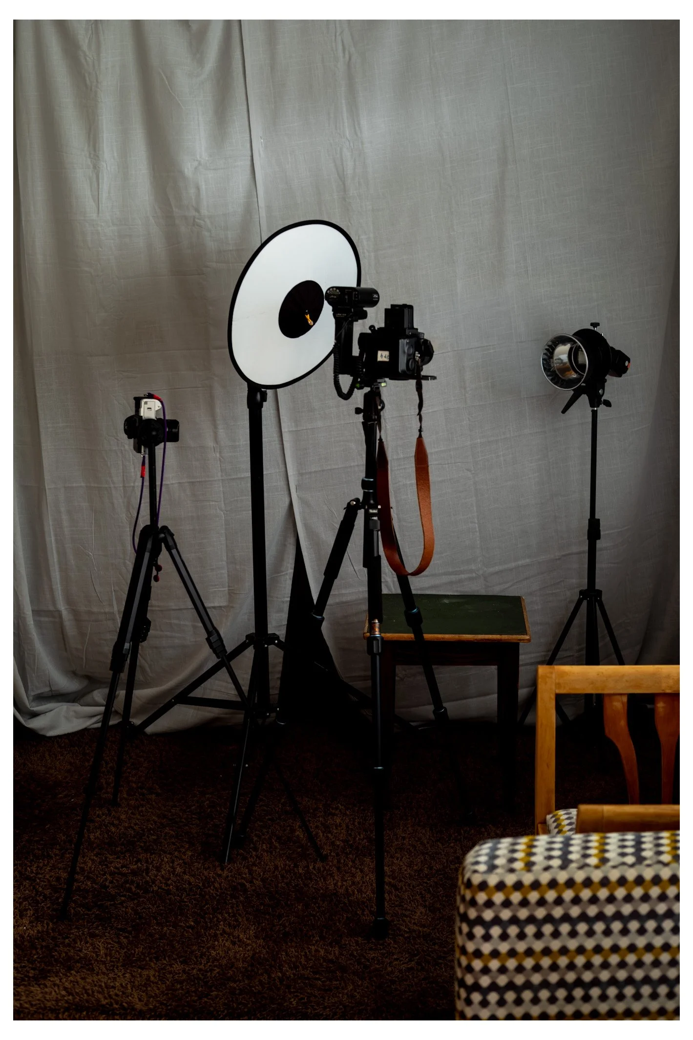 Fotostudio mit verschiedenen Beleuchtungs- und Kamerastativen vor einem beigen Hintergrund.