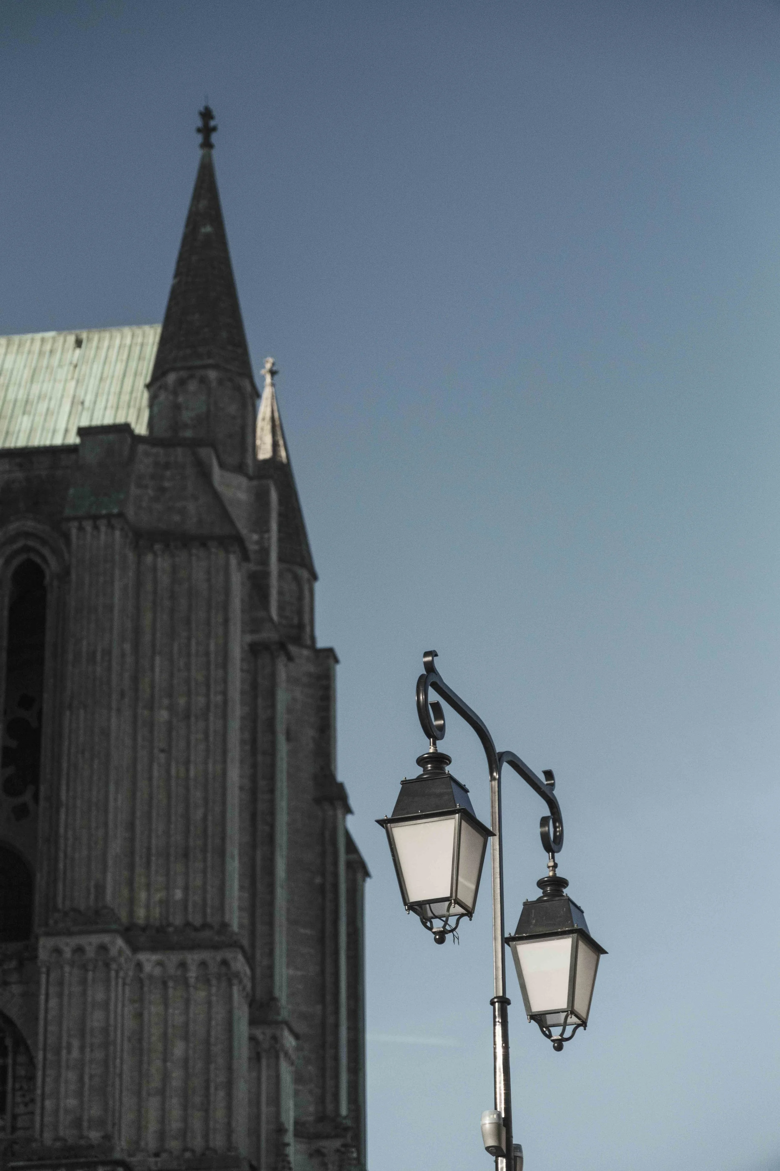Das Bild zeigt einen historischen Kirchenbau, im Vordergrund befindet sich eine straßenlaterne mit mehreren Laternen.