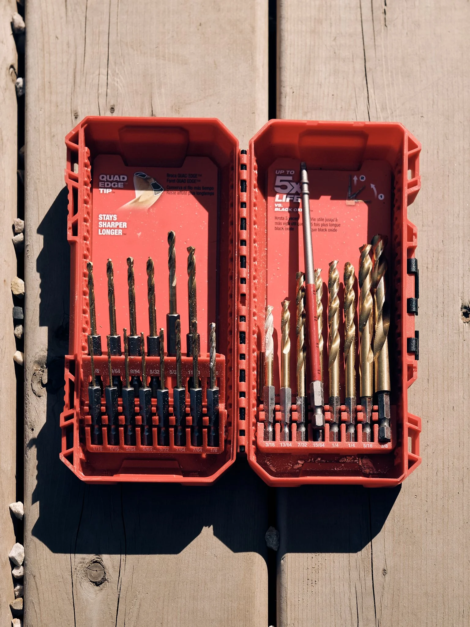 A plastic case containing a set of drill bits in various sizes, placed on a wooden surface outdoor.