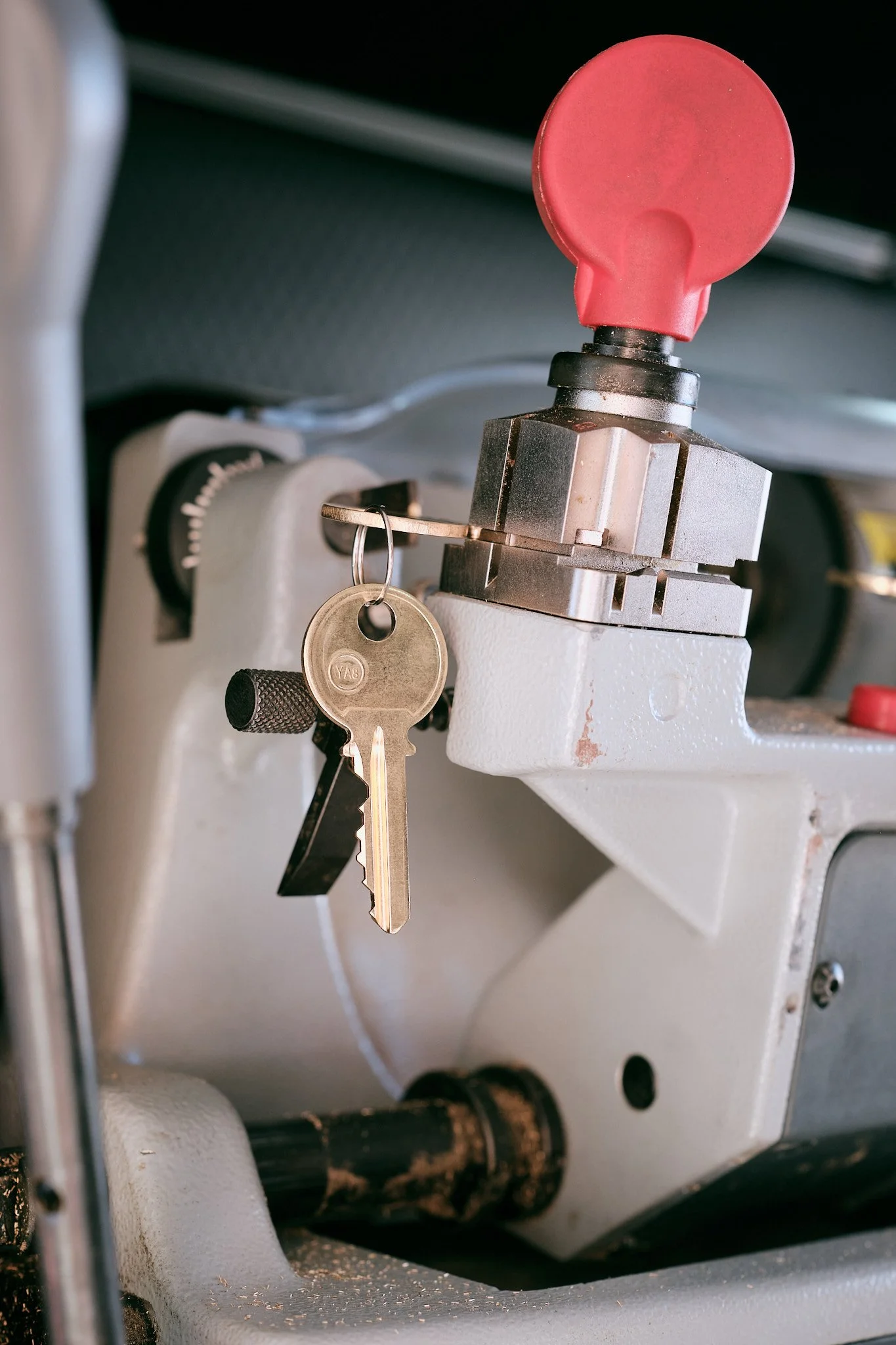 Close-up of a key inserted into a lock, attached to a yellow keyring, on a piece of machinery or equipment.