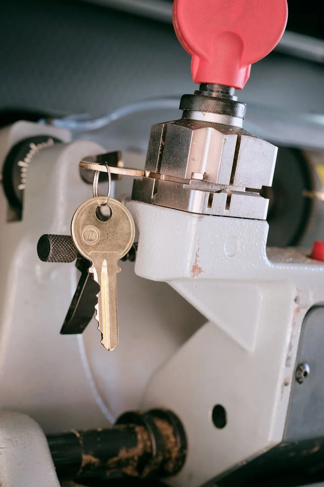 Close-up of a key inserted into a lock on a rekeying machine, with a keyring and key hanging from it.