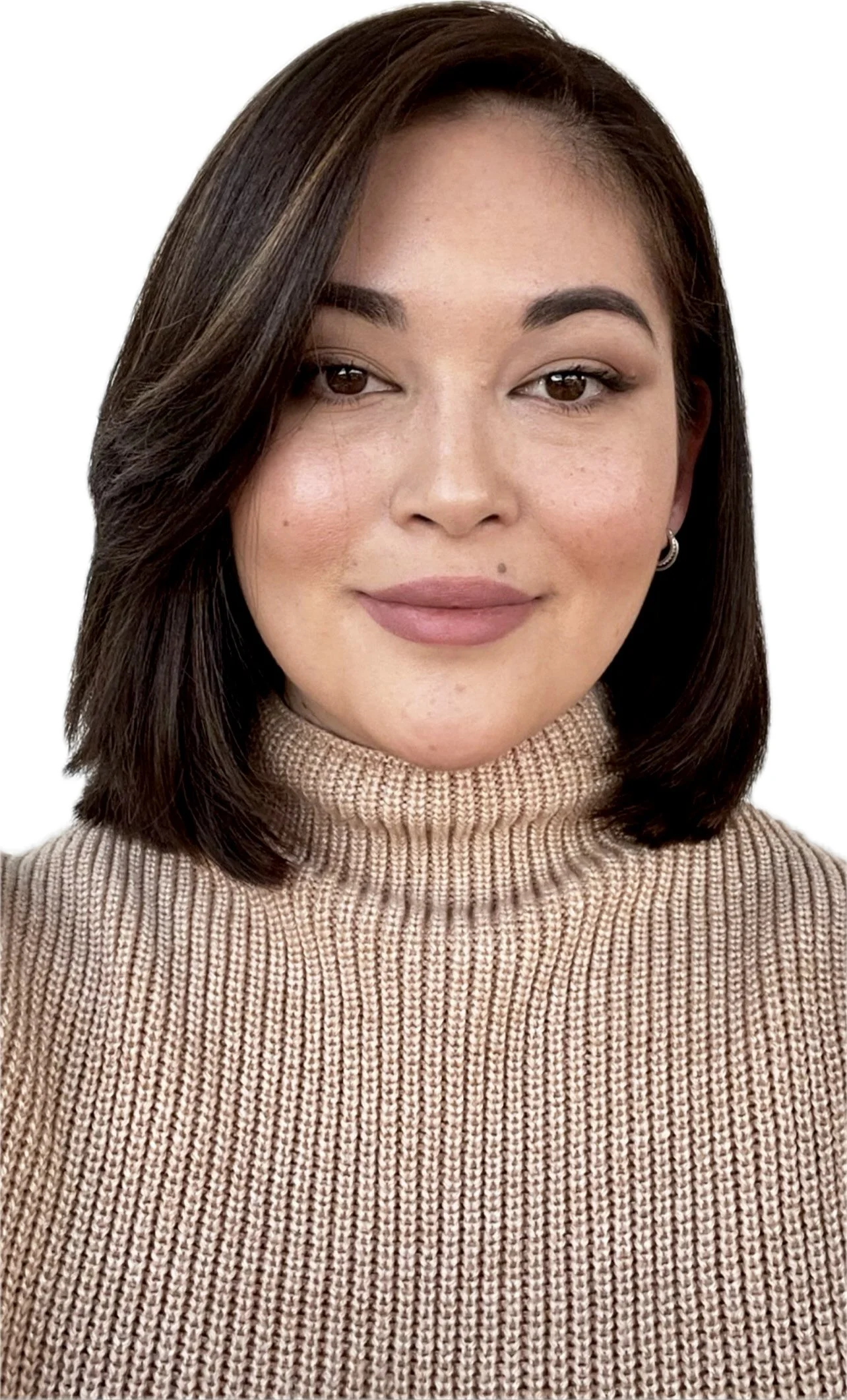 Close-up portrait of Zada with shoulder-length dark brown hair, wearing a beige turtleneck sweater, smiling softly, with makeup and earrings, against a white background.