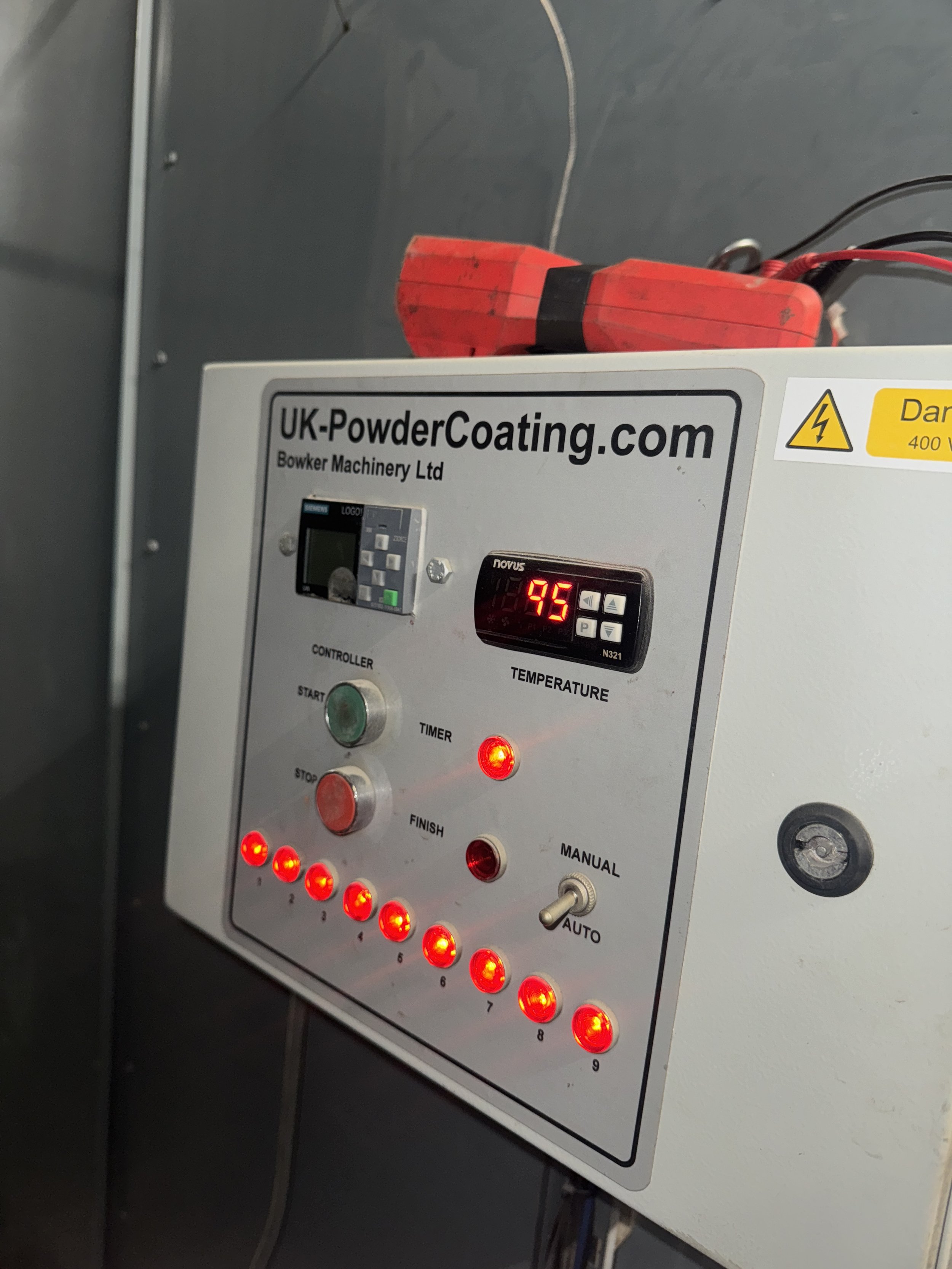 Control panel for powder coating equipment with buttons, digital display, and a red power supply unit on top, labeled with the website UK-PowderCoating.com.