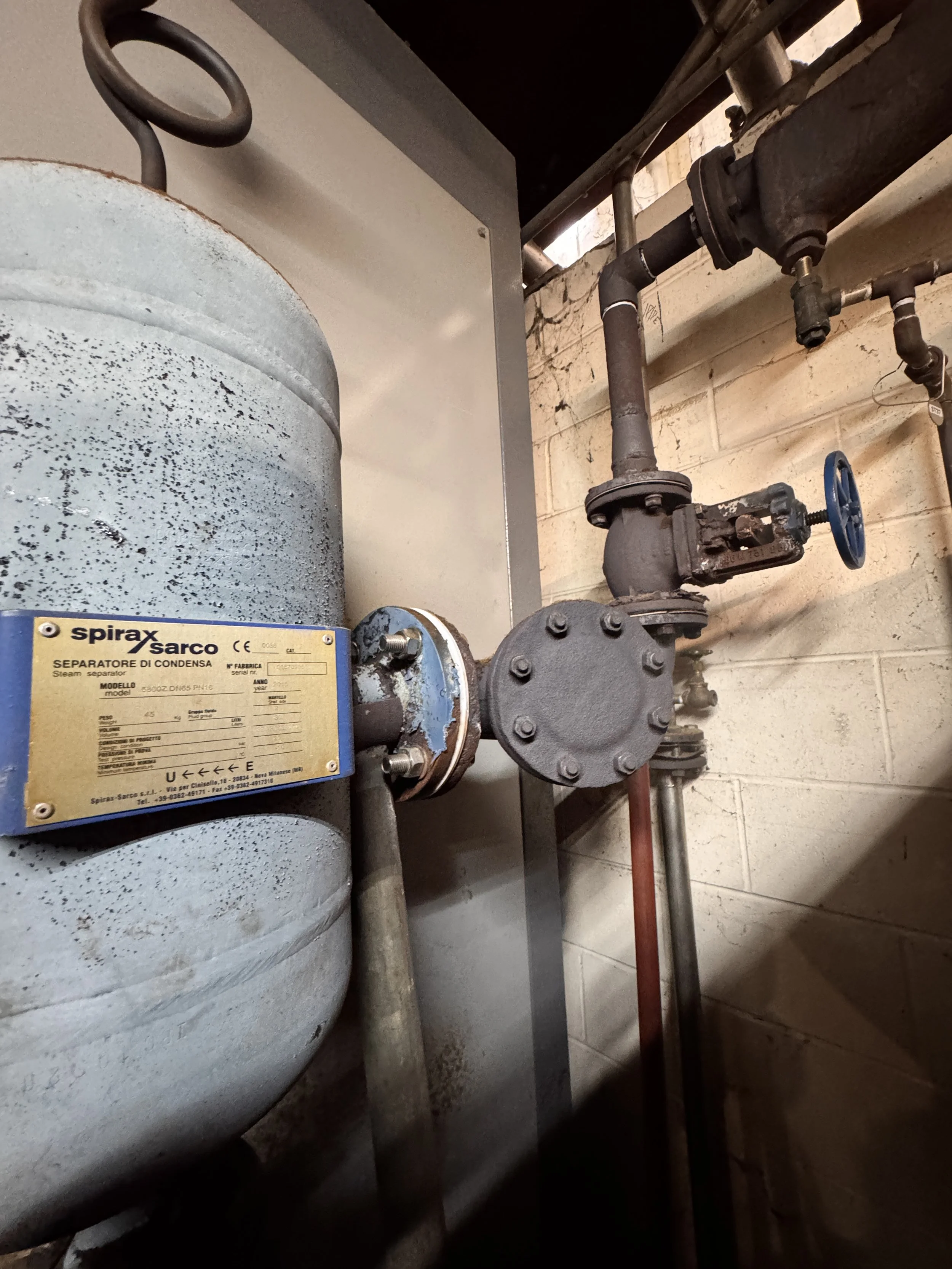 Steam separator tank and piping in a mechanical room.