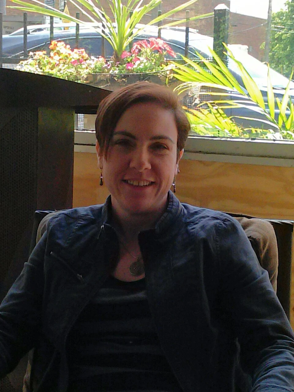 Portrait of a person seated indoors near a window with plants and flowers in the background, representing the consultant behind the practice.