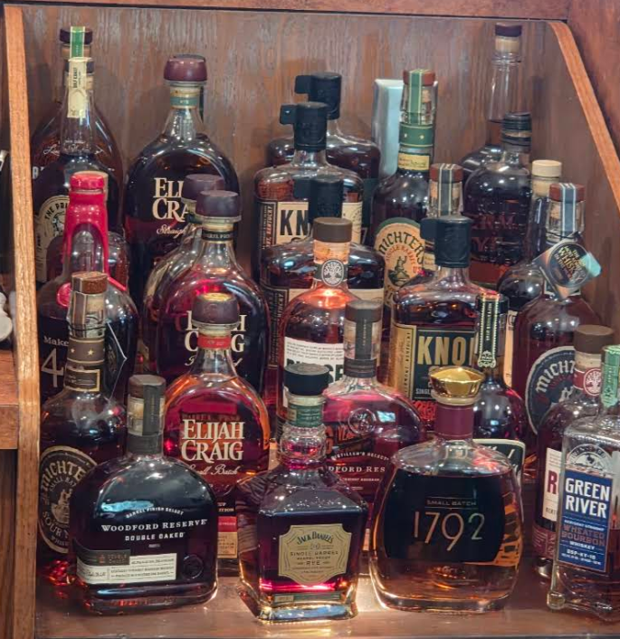 Collection of various whiskey bottles on a wooden shelf.