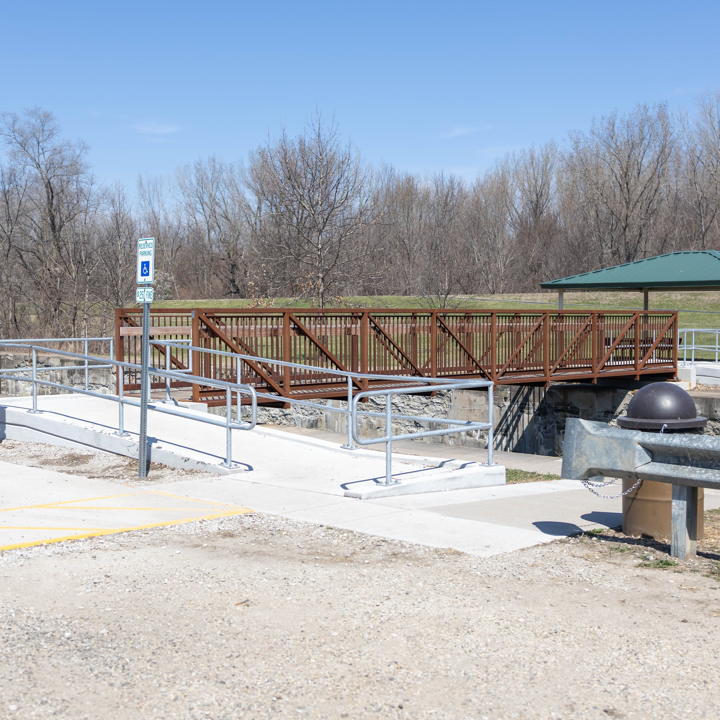 Empty accessible ramp and viewing platform at a park with trees and blue sky in the background.
