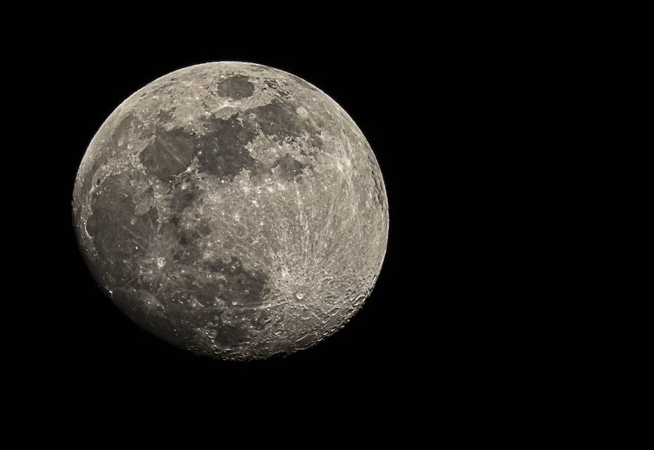 Close-up of the moon's surface showing craters and lunar terrain against a black sky.