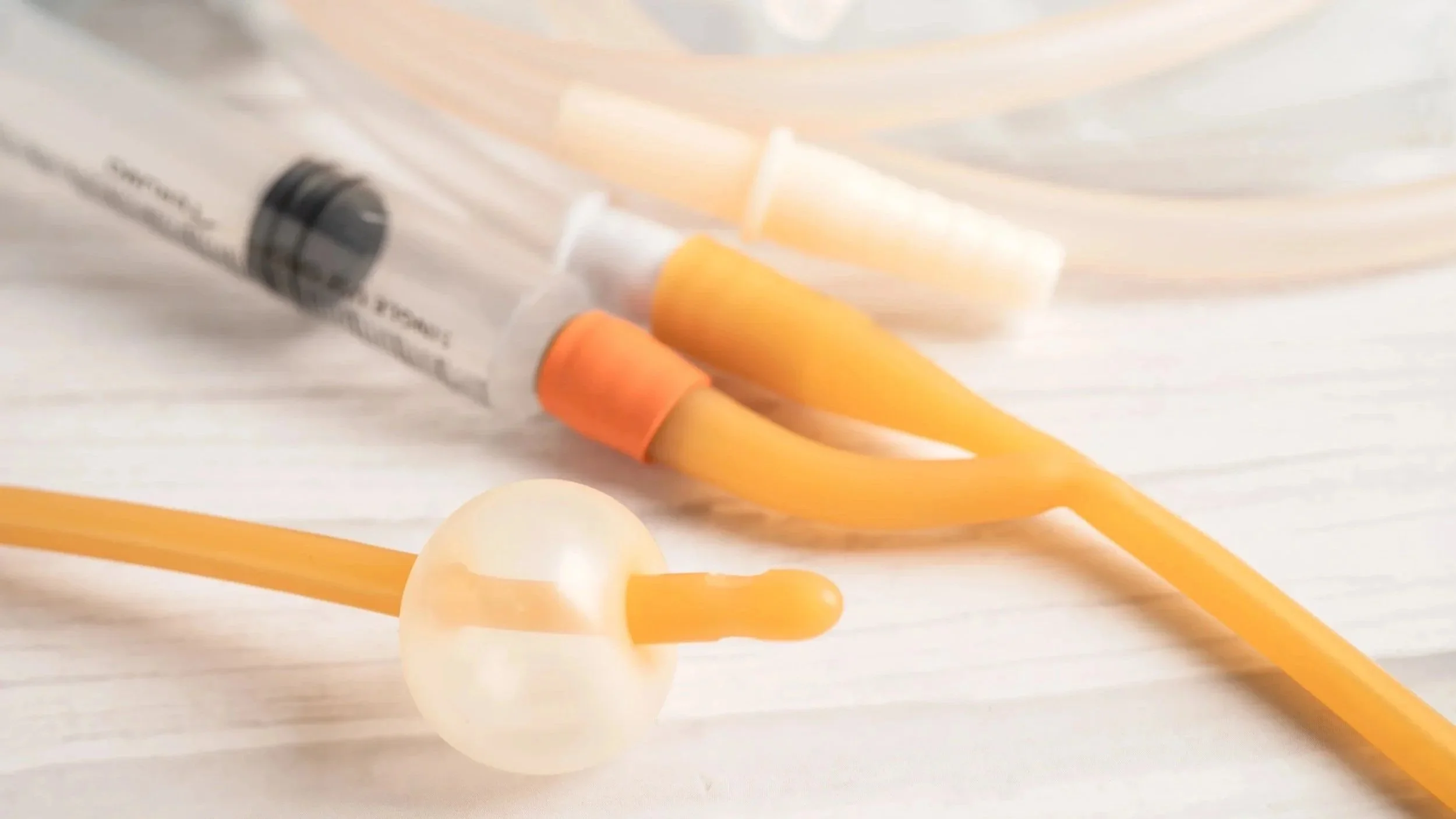 Siringa, capsule e bastoncini di medicina con colori in tonalità arancione, bianco e nero, posizionati su una superficie bianca e sfocata