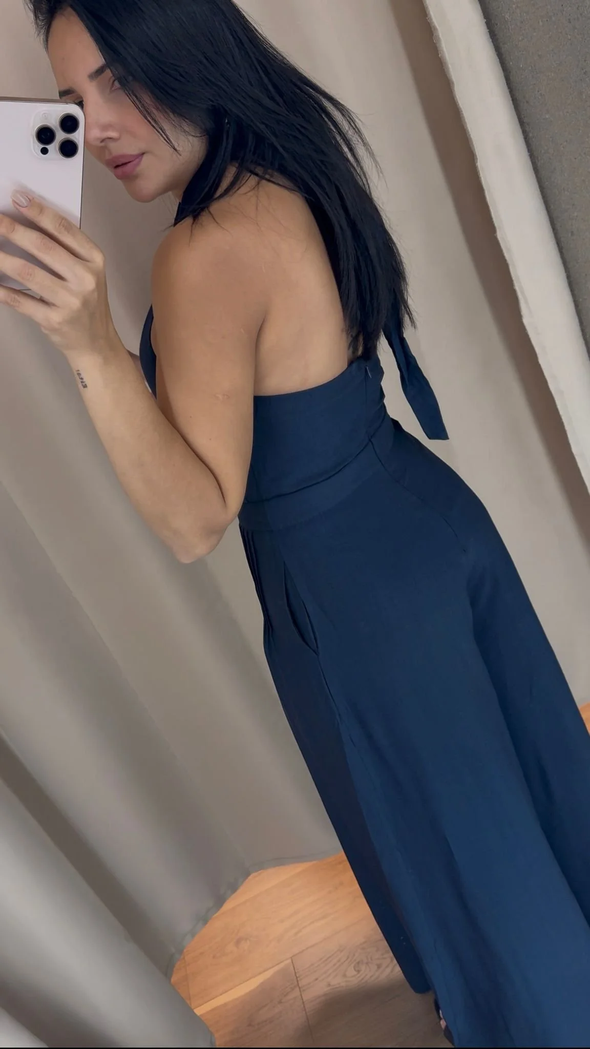 A woman with black hair taking a mirror selfie in a blue sleeveless top and blue wide-leg pants.