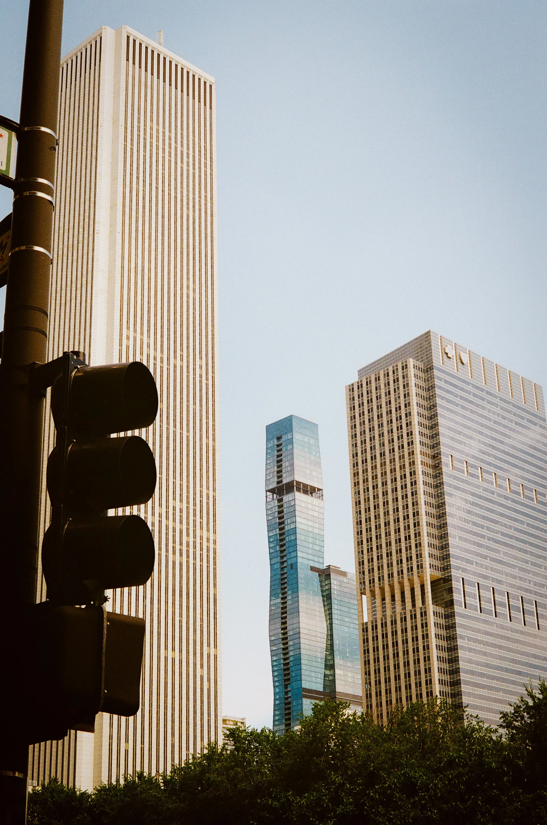 Cityscape with tall modern skyscrapers and a traffic light in the foreground.