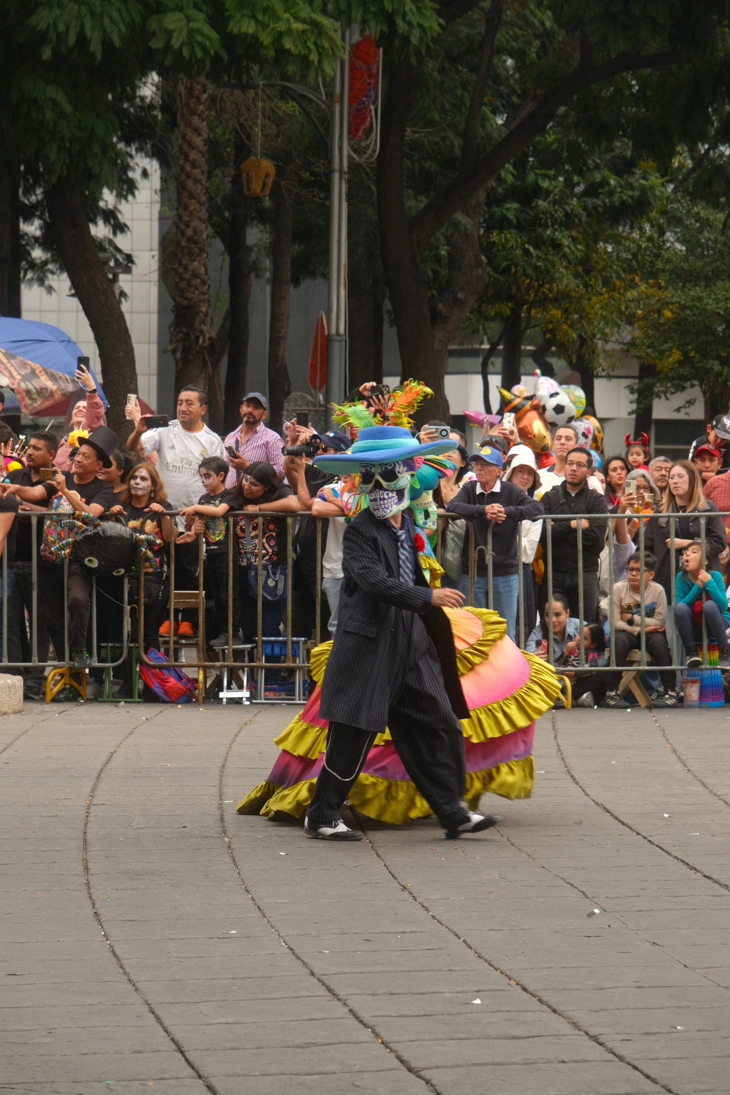 Performer with colorful costume and mask dancing in front of a crowd at a parade or celebration.
