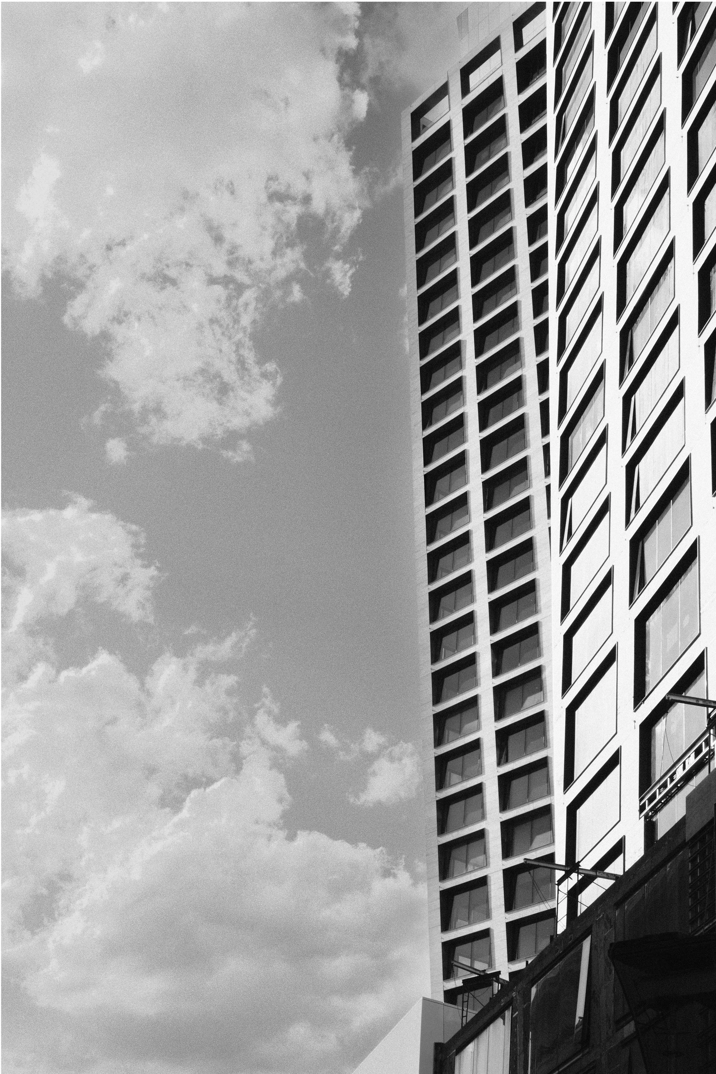 Tall modern building with a geometric facade next to a cloudy sky.