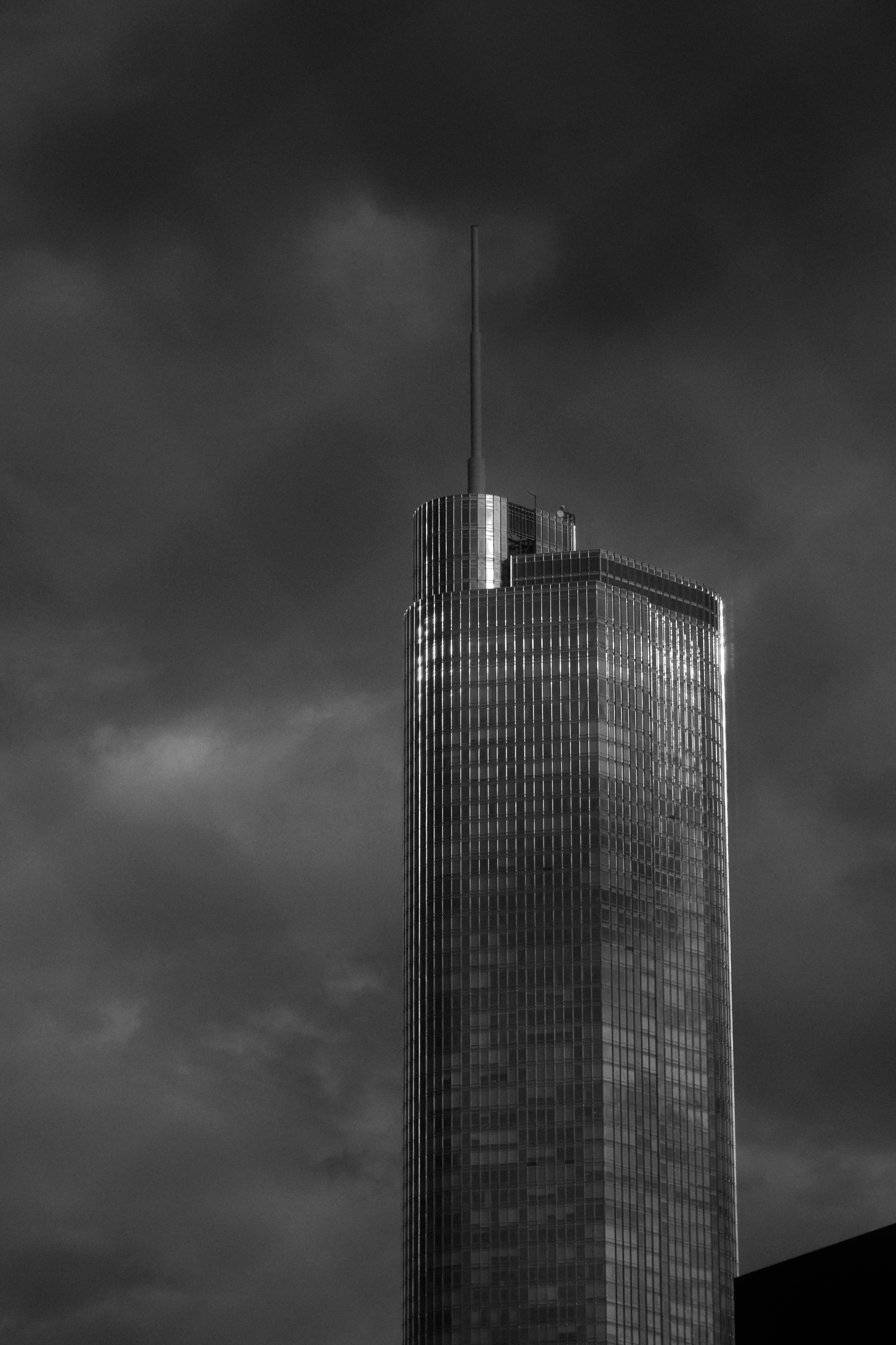 A tall skyscraper with reflective glass windows against a dark, cloudy sky.