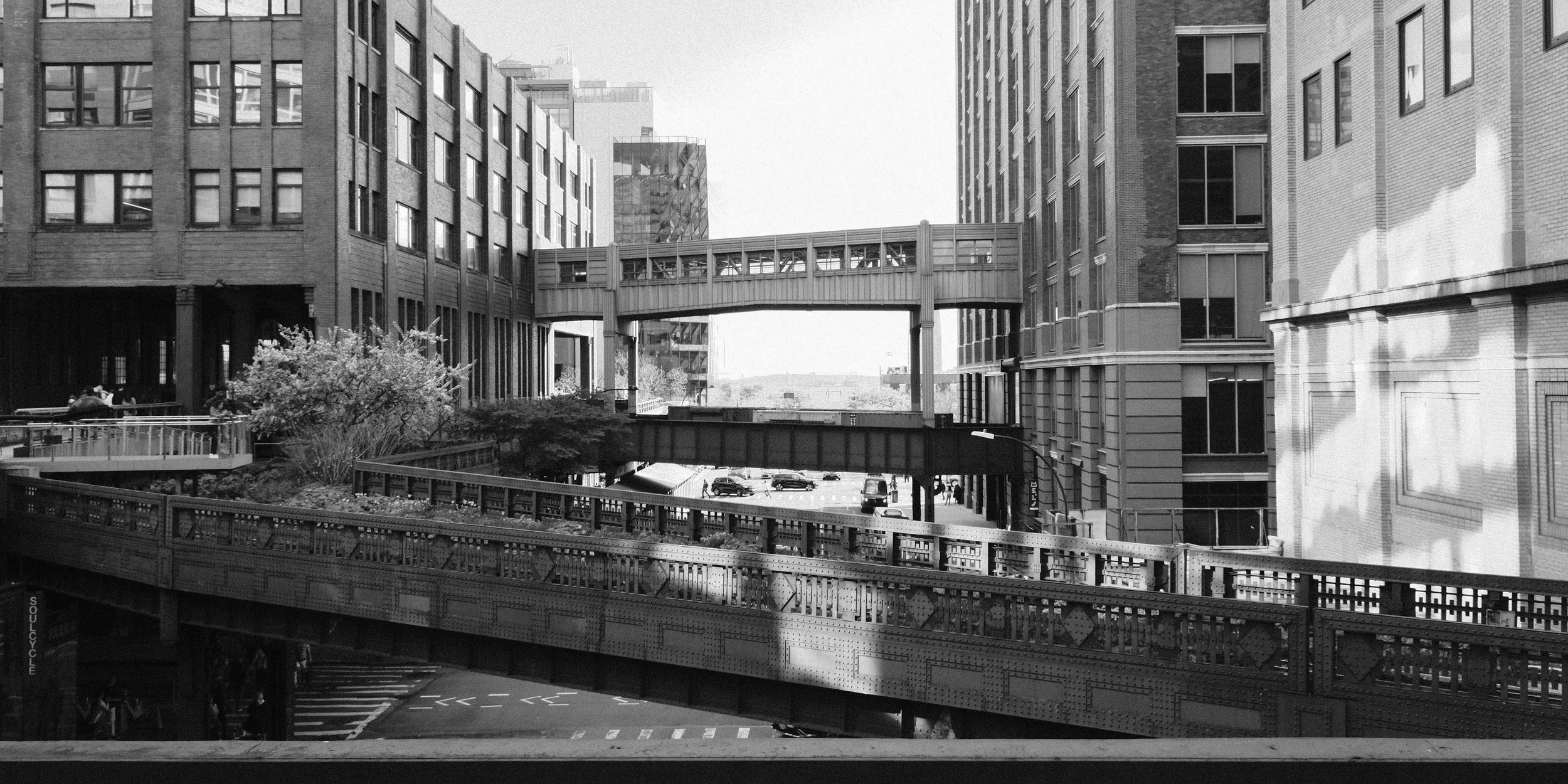 Black and white photo of urban cityscape with multiple modern buildings, bridges, and streets, featuring a mix of architectural styles.