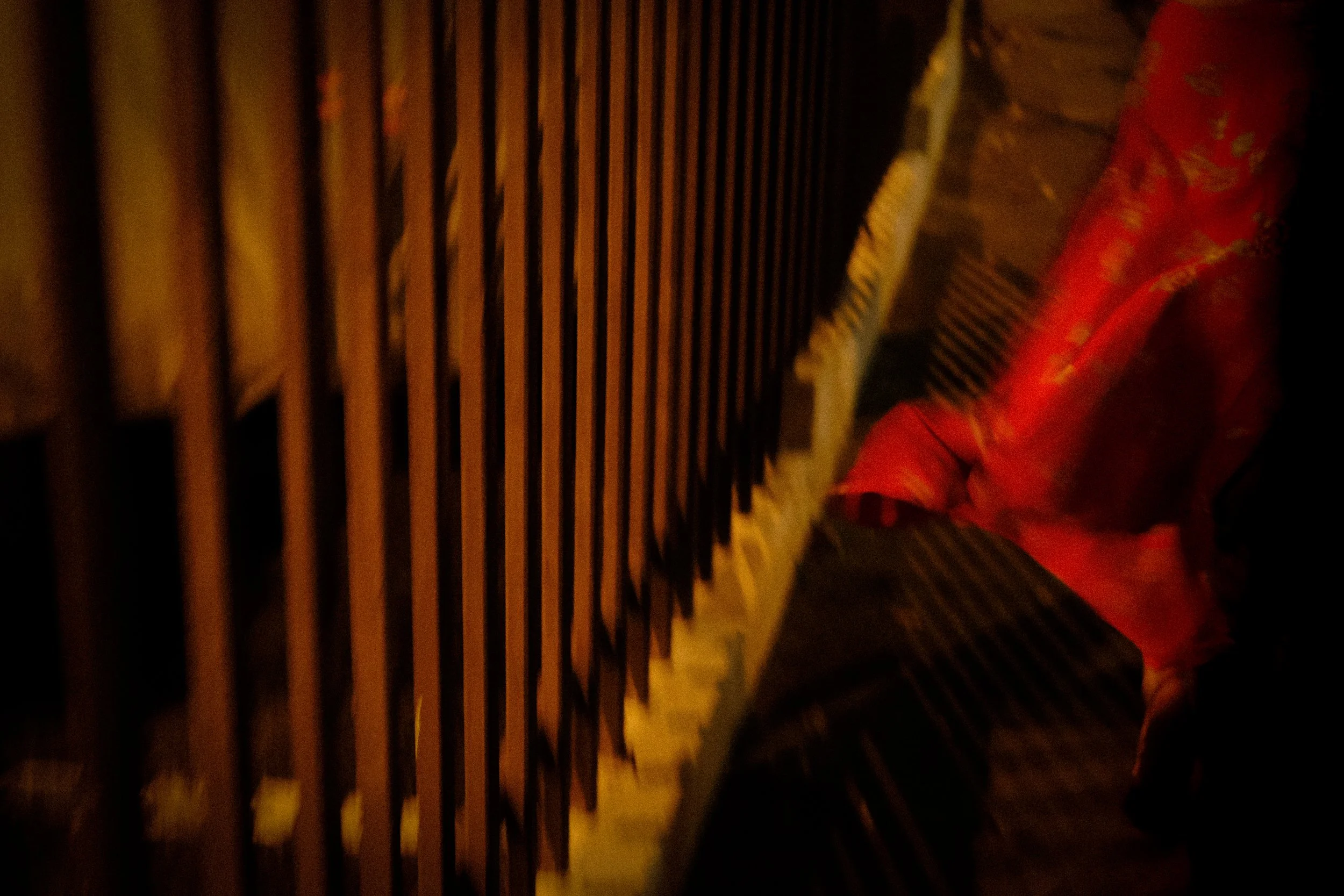 A close-up of a black metal fence with vertical bars, and a red cloth or garment draped over a surface next to the fence, in a dimly lit setting.