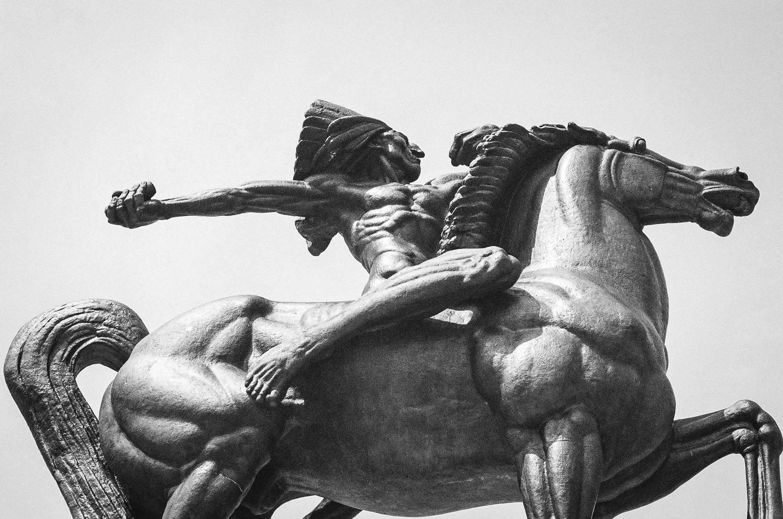 Black and white photo of a mounted Native American warrior holding a spear.