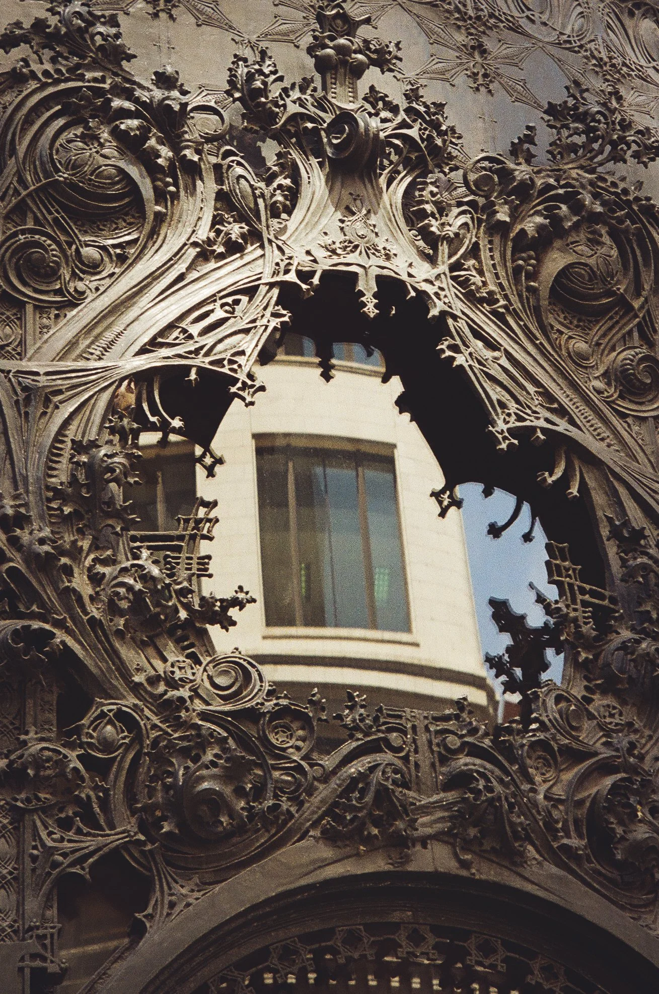 Ornate metalwork or architectural detail with a reflection of a building and window in the center.