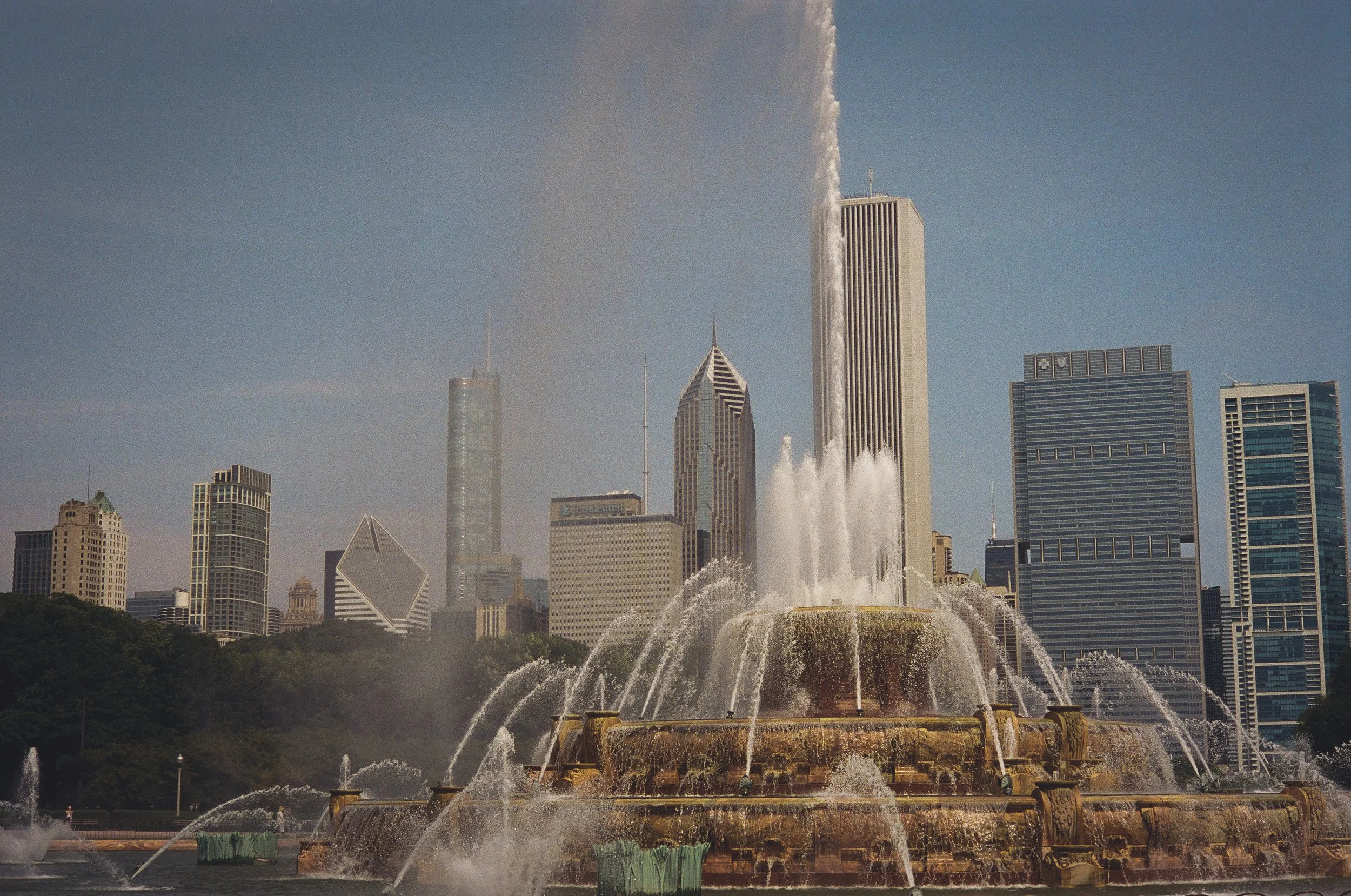 Fountain in a park with skyscrapers in the background on a sunny day in a city.