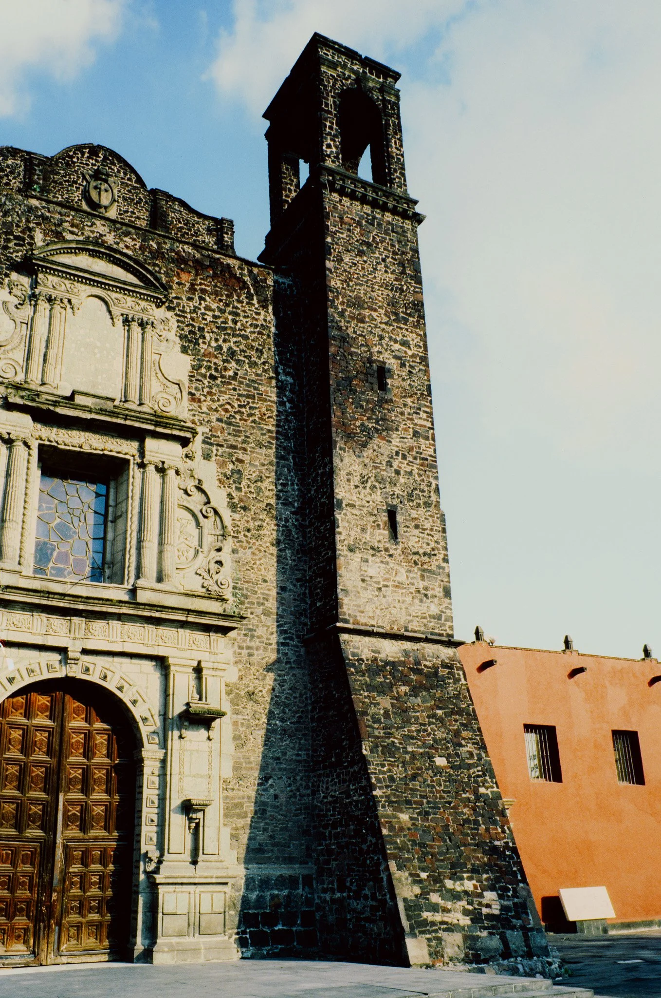A historic stone church with ornate details and a tall bell tower against a partly cloudy sky.