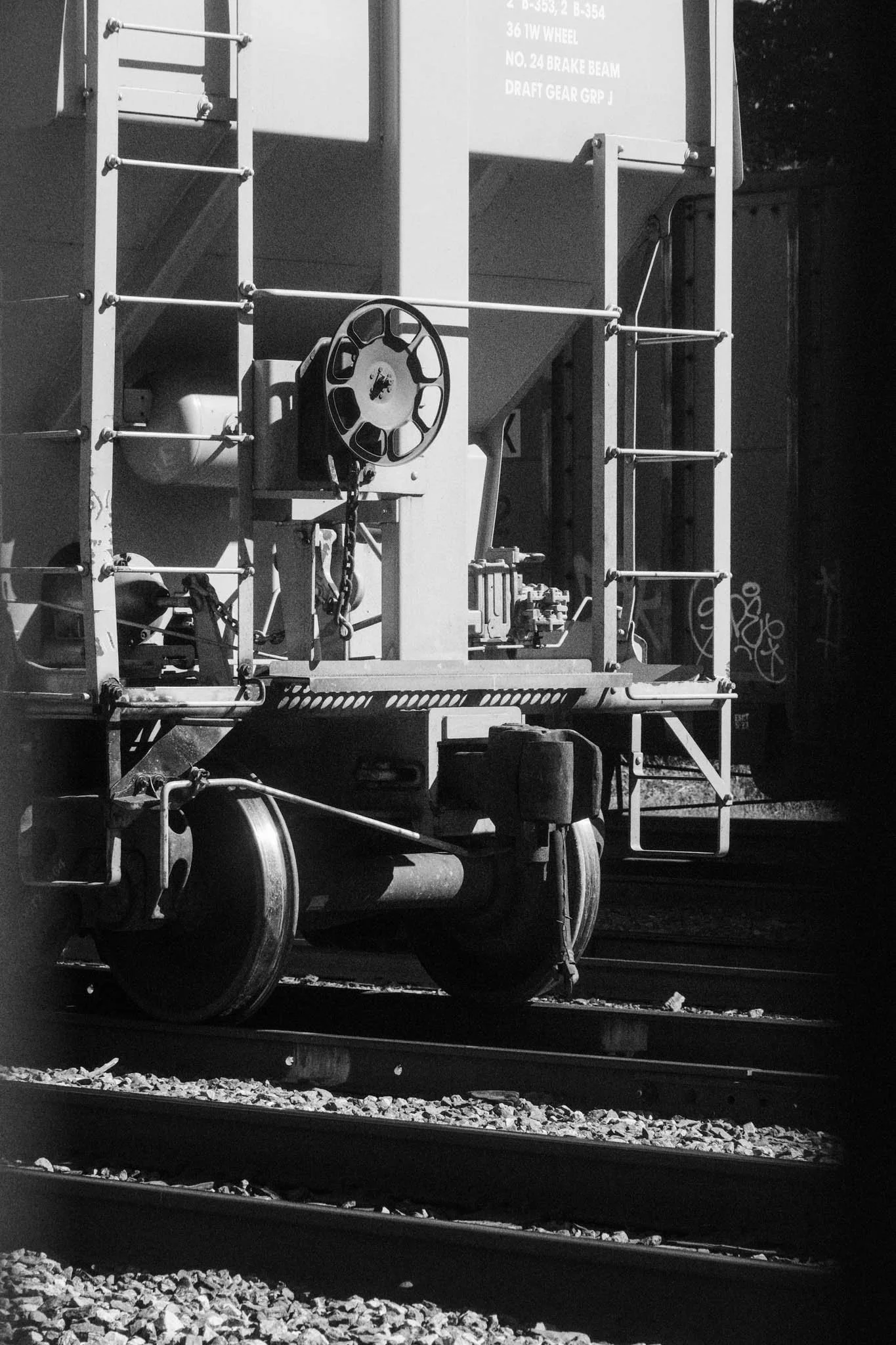 Black and white photo of a railway maintenance train car on train tracks, with various mechanical parts and equipment.